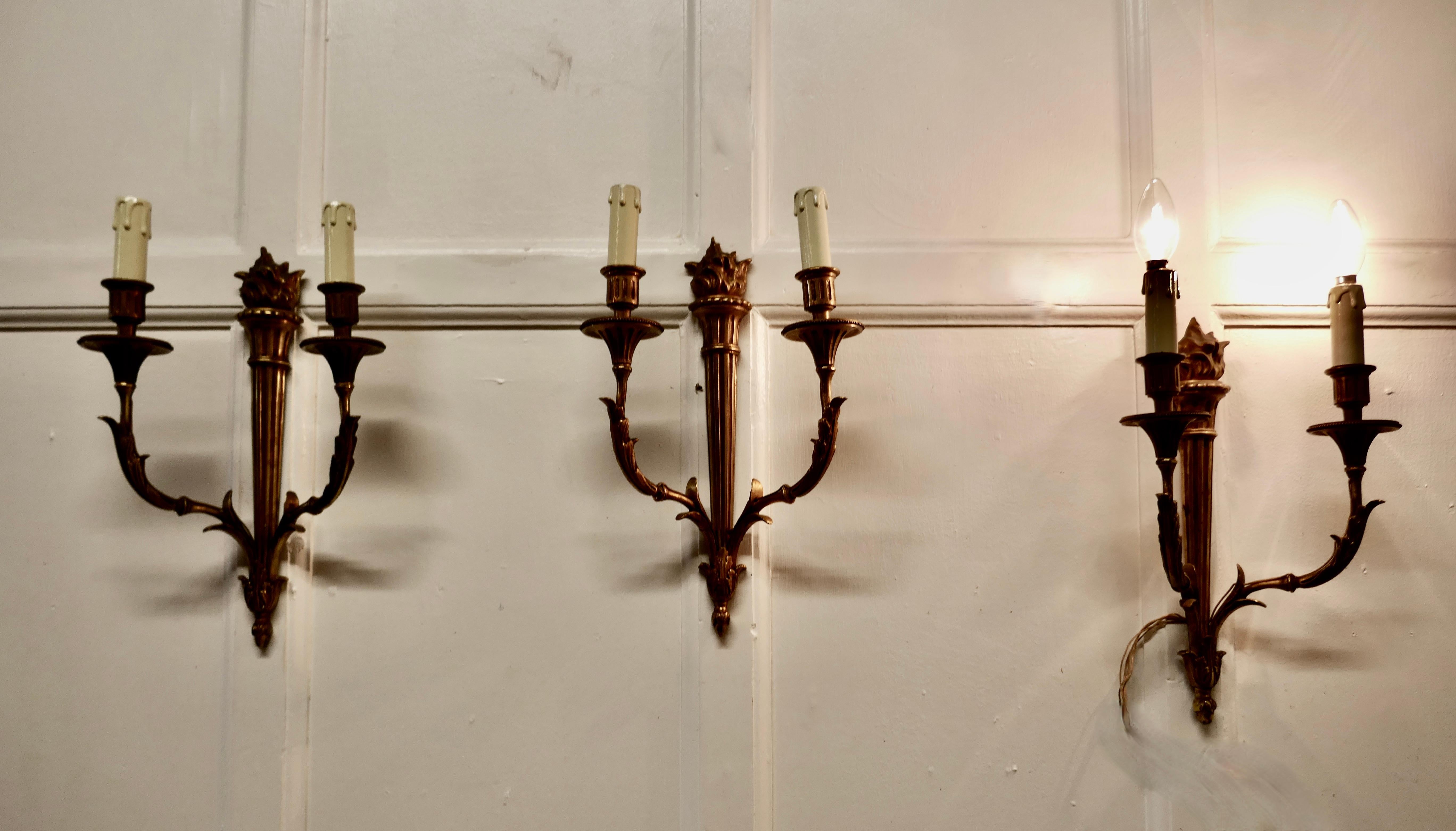 Set of 3 French neo classical large brass twin wall lights


A very handsome set of 3 large heavy brass wall lights, the lights are in the classical style of a Lighted torch with acanthus leaf branches 
Each light has 2 branches each with a