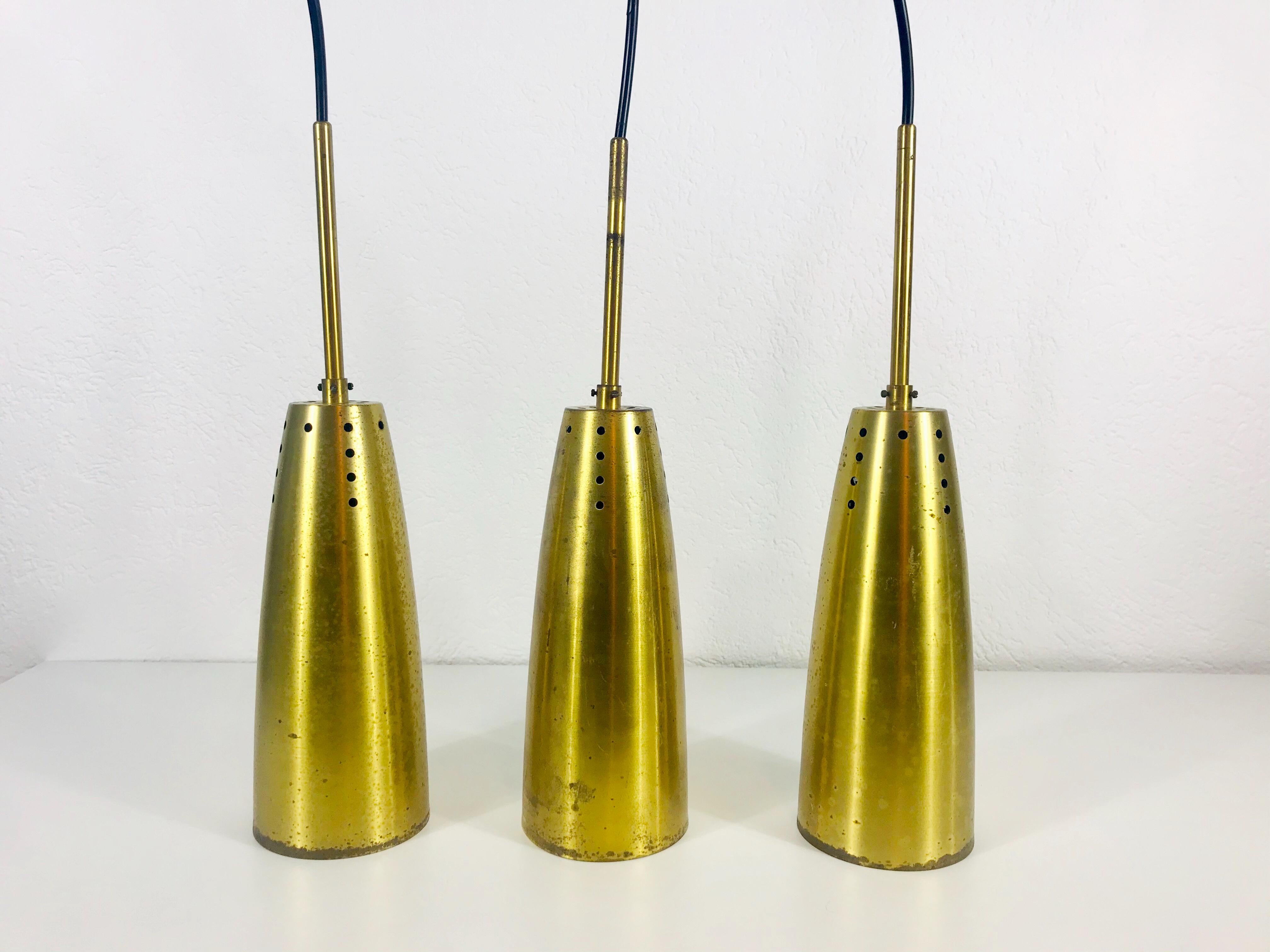 Set di tre rarissime lampade a sospensione realizzate in Germania negli anni Cinquanta. L'illuminazione è realizzata in ottone e ha lo stile del marchio italiano Stilnovo. Ha molti piccoli fori che creano una luce meravigliosa. L'illuminazione