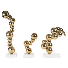 Conjunto de 3 esculturas de metal dorado con bases de mármol, del siglo XXI.
