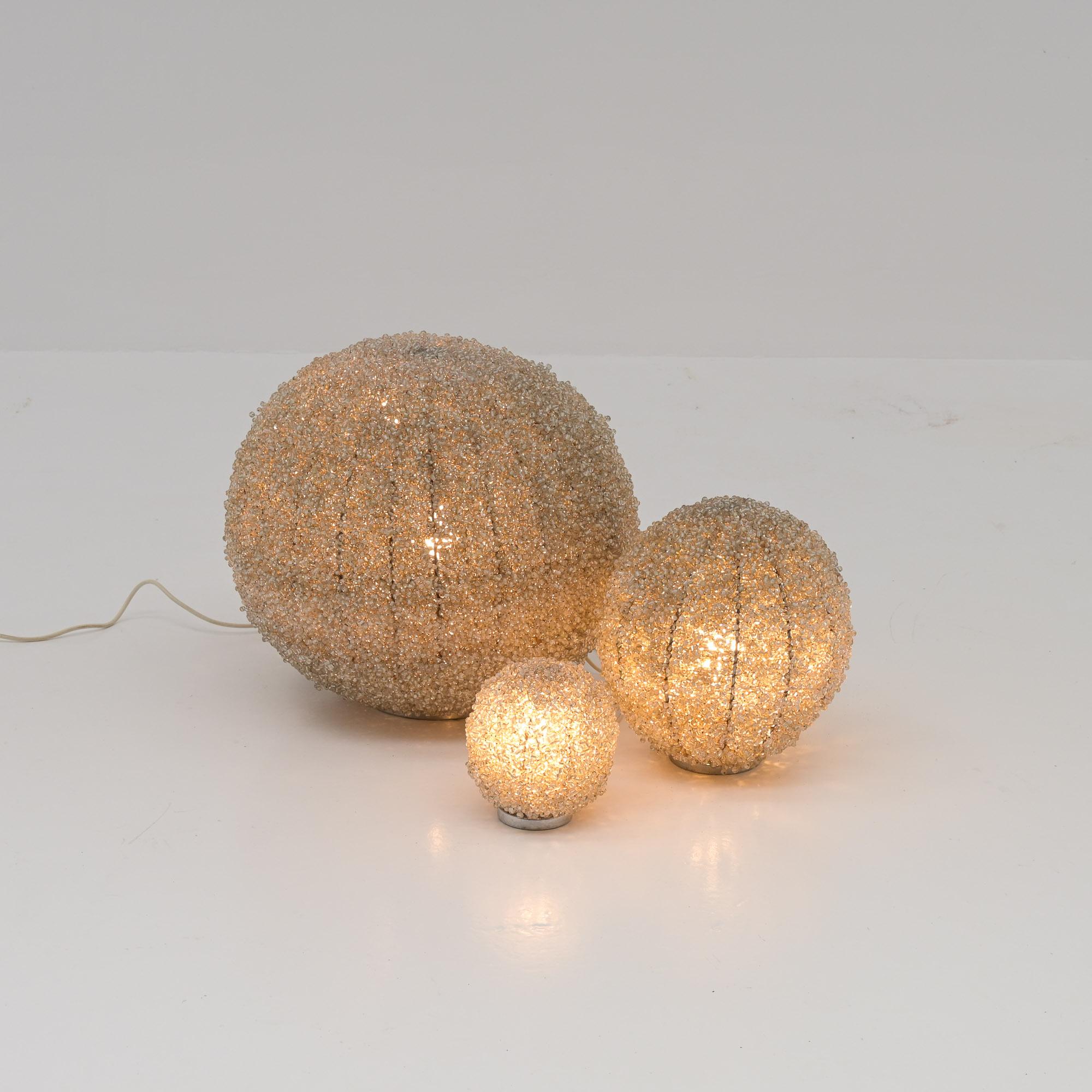 Questo fantastico set di lampade in vetro-perla risale agli anni '70. Sono completamente fatti a mano, immagina che lavoro sia stato. Le perle di vetro combinate con la luce danno un effetto molto bello e unico.

Le lampade si adattano a qualsiasi