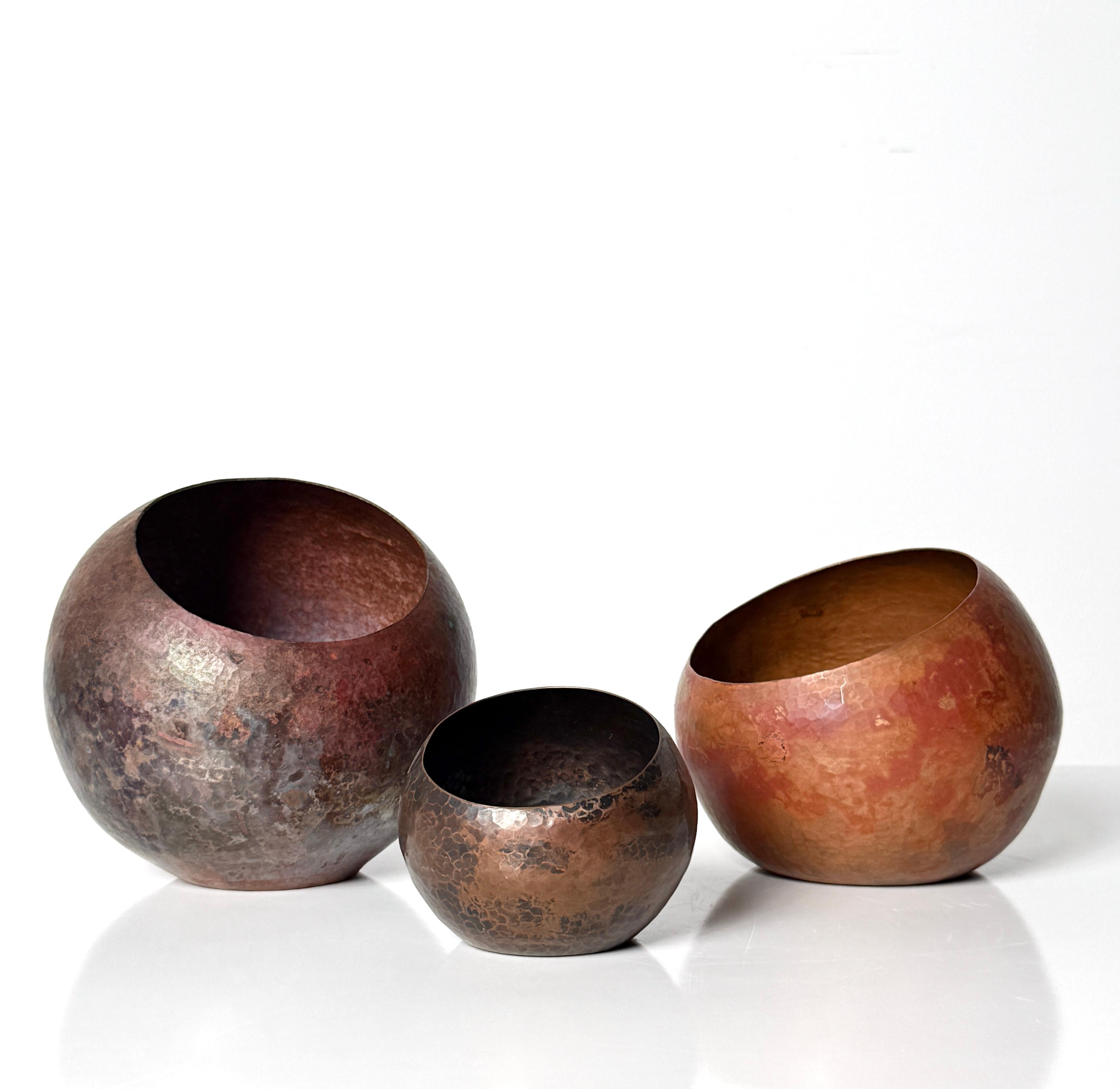Grouping of three sculptural round hammered copper vessels 
In the style of Santa Clara del Cobre Michoacán region
Mexico circa 1960s

Handcrafted asymmetrical bowls with off center openings in varying size and finish
2 retain their original