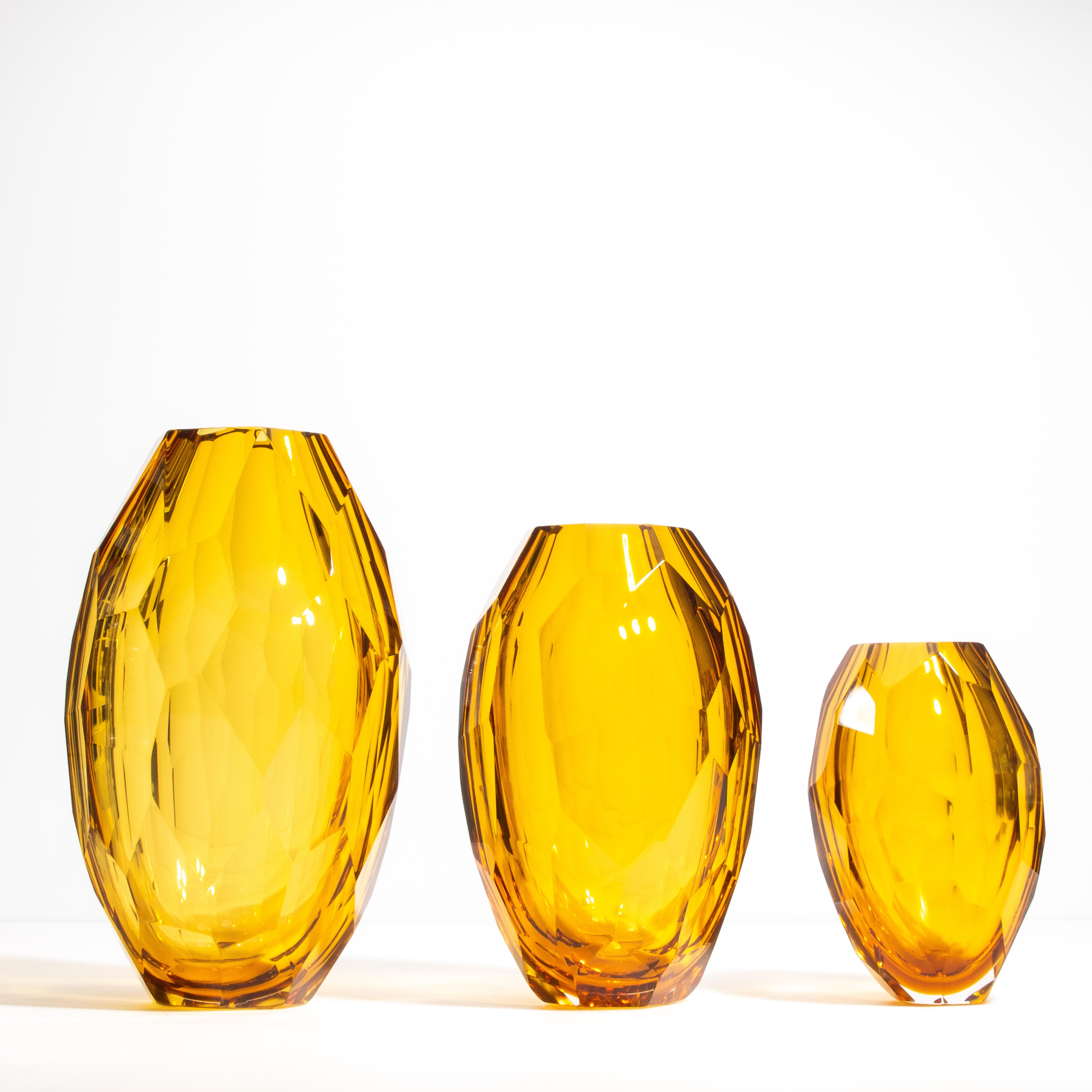 Eleganza sublime con i nostri vasi d'ambra sfaccettati, un capolavoro dell'arte del vetro di Murano. Questo squisito Trio, meticolosamente realizzato da abili artigiani, cattura l'essenza del lusso senza tempo. La ricca tonalità ambra dorata di ogni