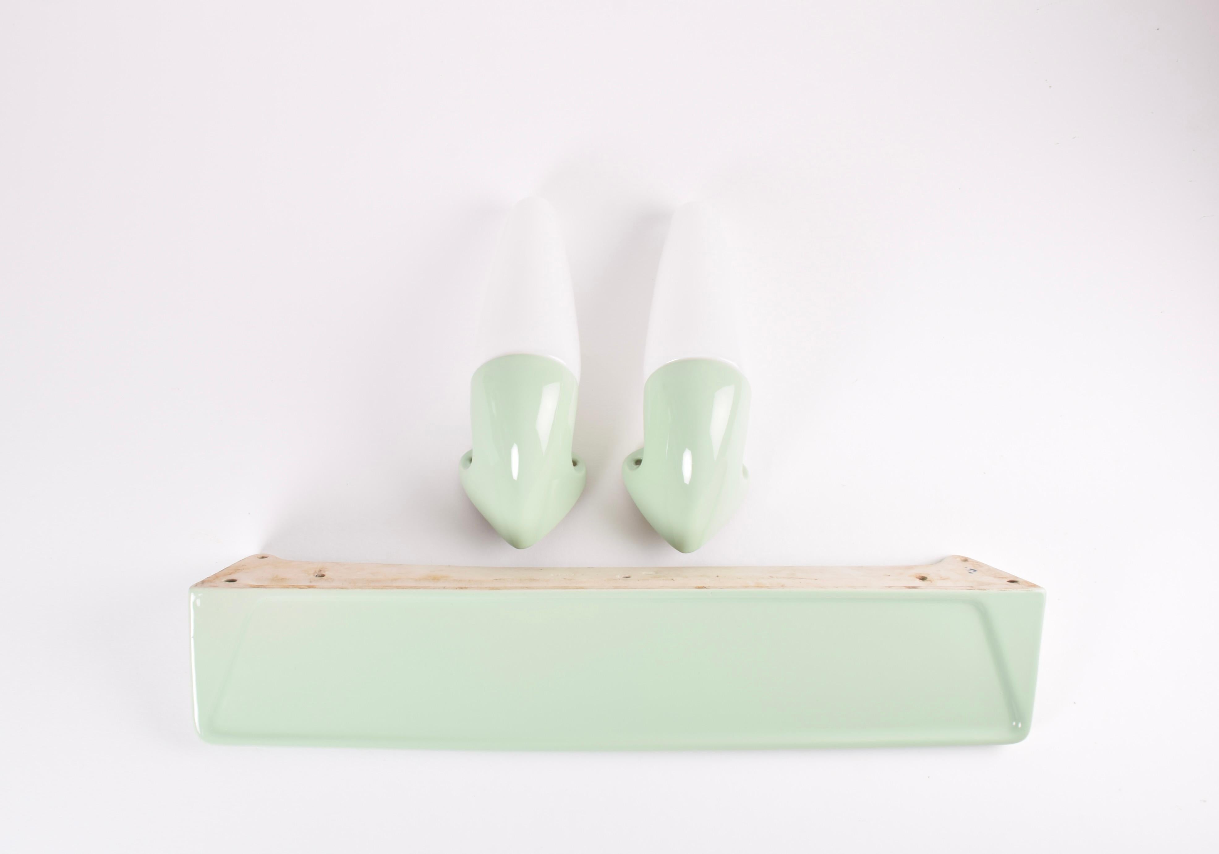 Set of two original vintage wall sconces and a matching shelf from Ifö, Sweden, made circa 1950s to 1960s. They come in the more rare to find pale green color version. The glass screens are made from white opaline glass. Perfect for the