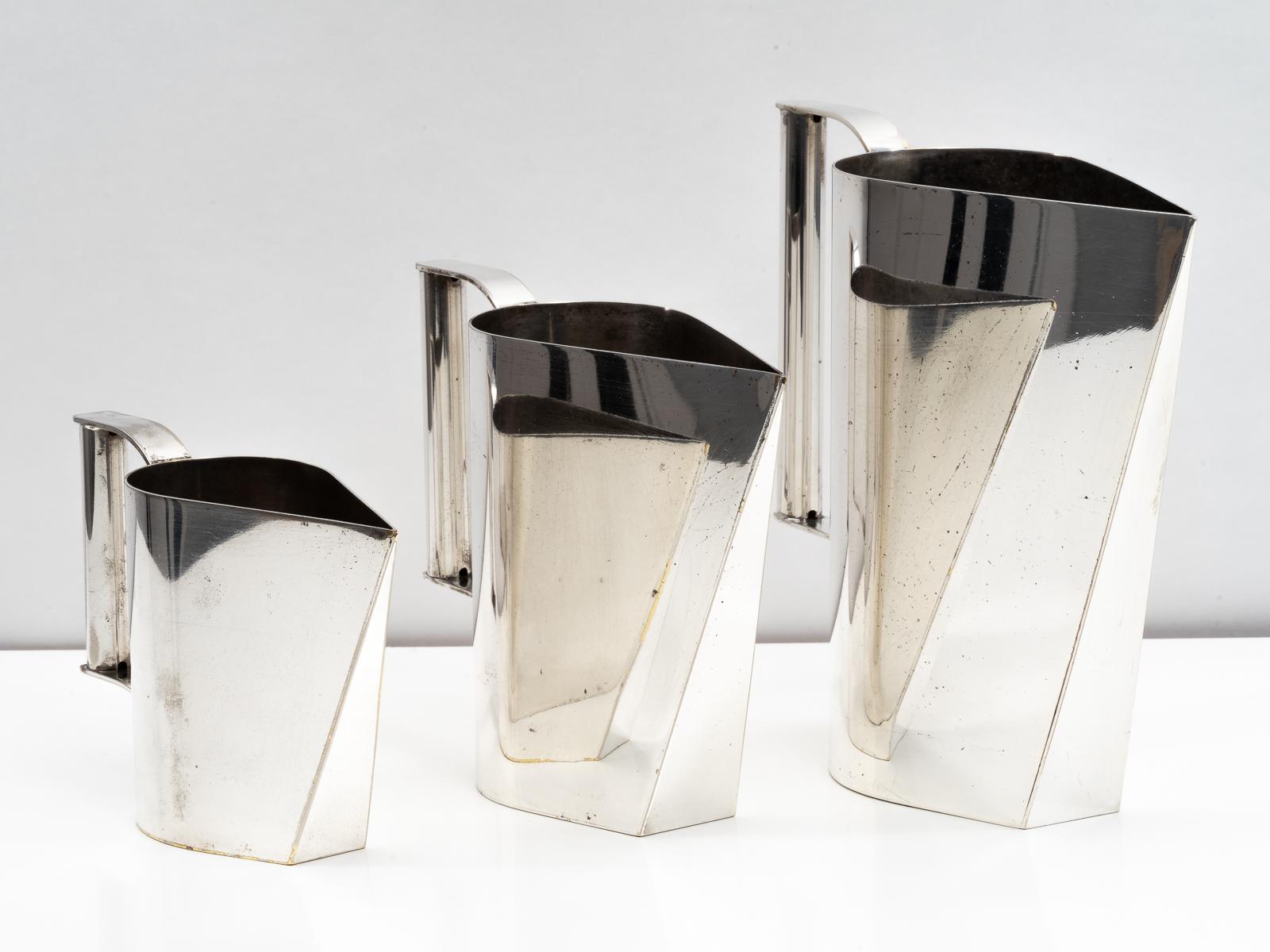 A unique and beautiful set of three Italian silver plated brass pitchers or carafes attributed to Cini Boeri from the mid-1970s. Expertly combining hard angles with soft curves, these elegant display pitchers work well as a grouping or individually.