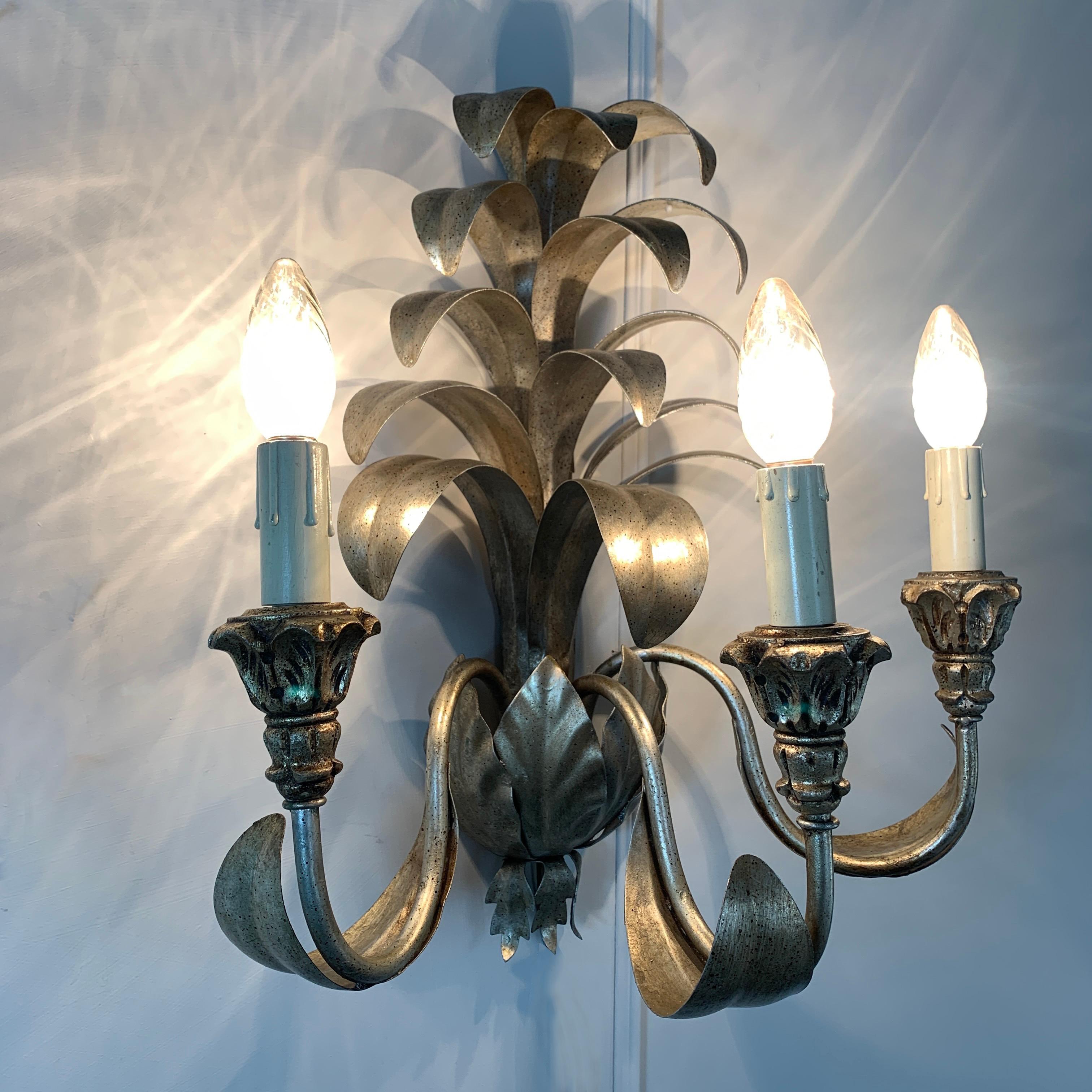 Set of 3 Italian pineapple tole leaf wall sconces
Italian, late 20th century
Large warm silver gilt metal leaf fronds stand tall from the centre of the lights
There are 3 silver gilt metal arms with giltwood cups to hold the 3 bulb holders
These