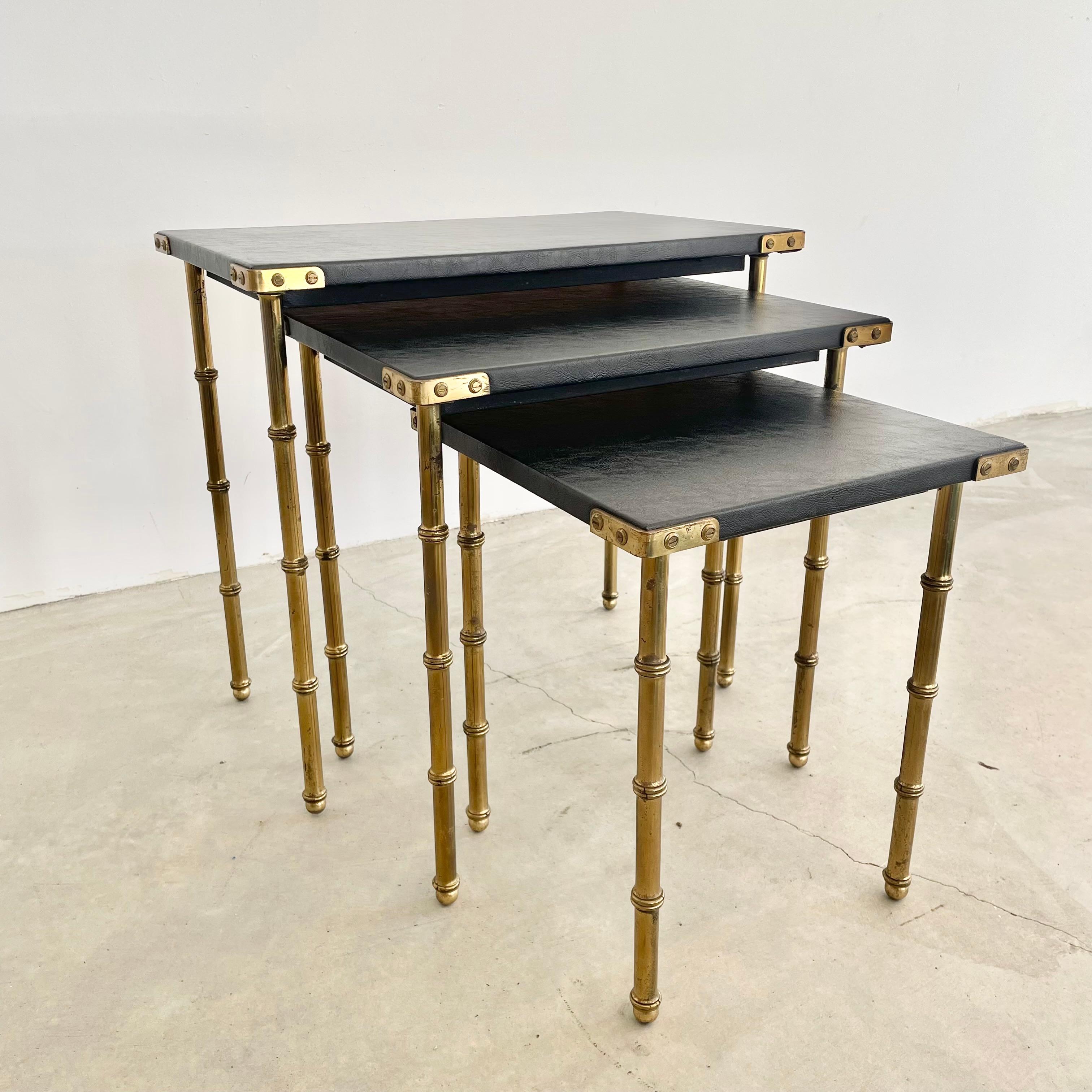 Beautiful set of 3 nesting tables by French designer Jacques Adnet. Table tops are wrapped in black skai with brass legs and hardware and brass ball feet. Tabletop edges are brass brackets with brass screw detailing. Great vintage condition. Very