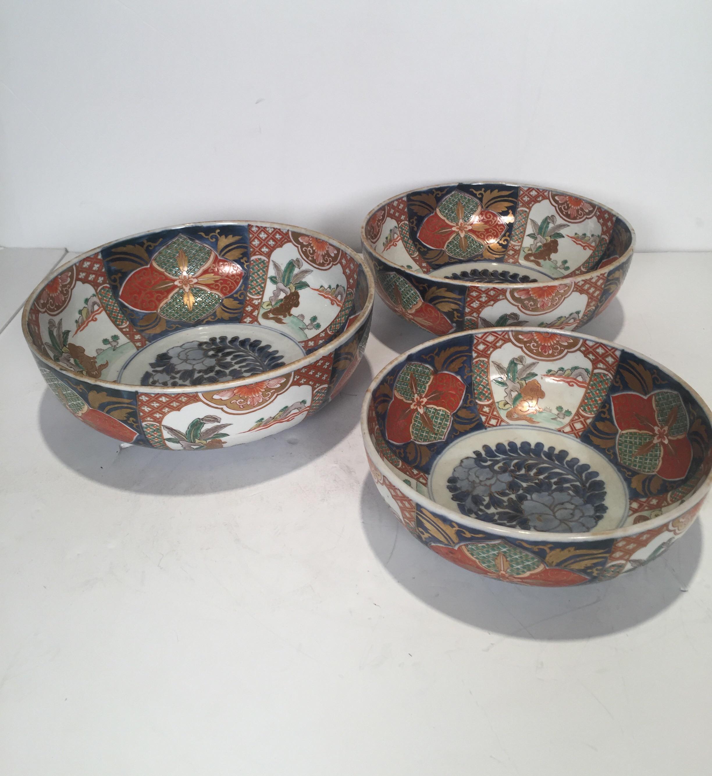 A rare set of three hand painted Imari porcelain graduated sized bowls with the same hand painted scenes and decoration on each. The large is 12 inches in diameter, with the medium 11 inches and the smallest 10 inches. Meiji period, circa 1880s.