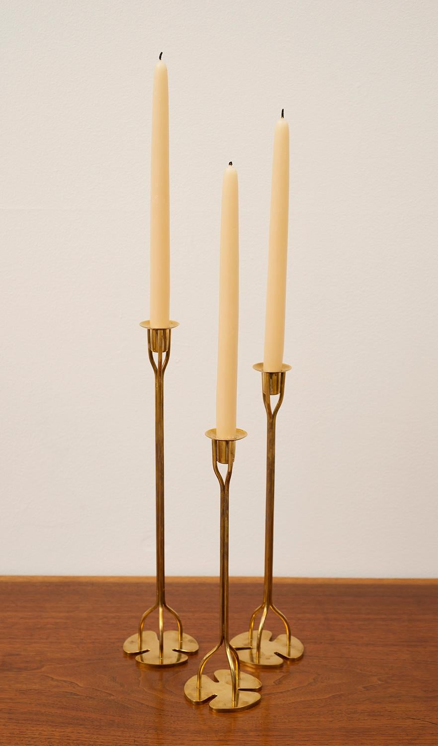 Three Josef Frank candlesticks by Svenskt Tenn of Sweden in brass with clover bases and wonderful patina. Sweden, 1950s.