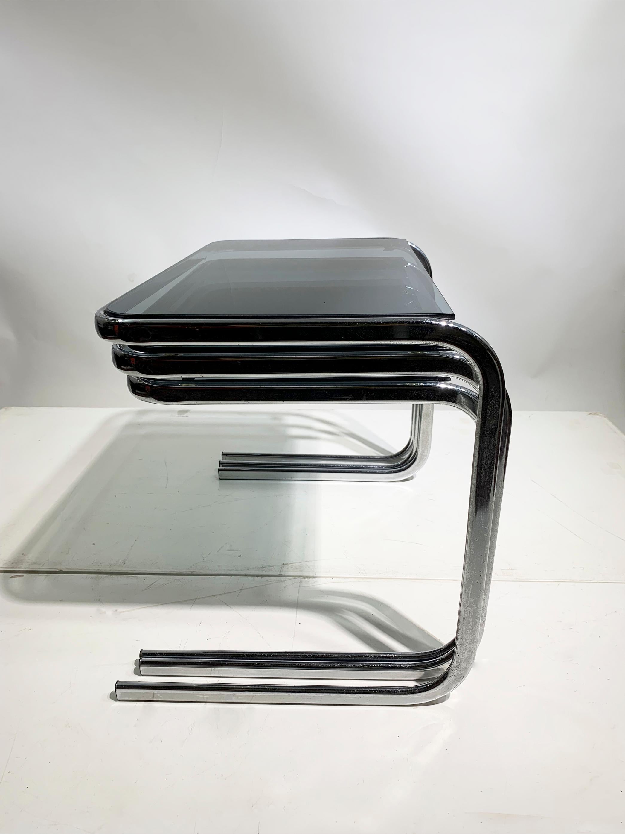 A sophisticated set of nested tables from the late 1970s, showcasing Italian craftsmanship in chrome and smoked glass, exuding post-modern elegance. 
The cantilever design adds a touch of luxury and modernity. 
The smoked green glass is expertly