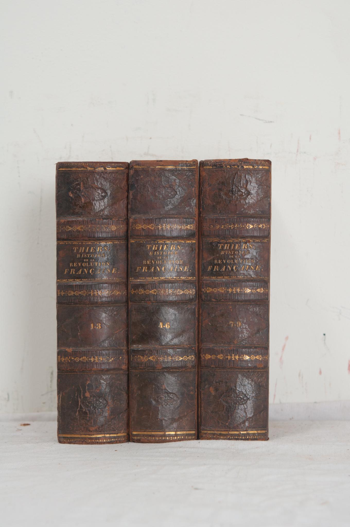 A collection of three volumes on the French Revolution by M. A. Theirs. This set of books is bound in leather with the title, author, and respective volume number stamped in gold lettering. The pages have signs of discoloration, make sure to view