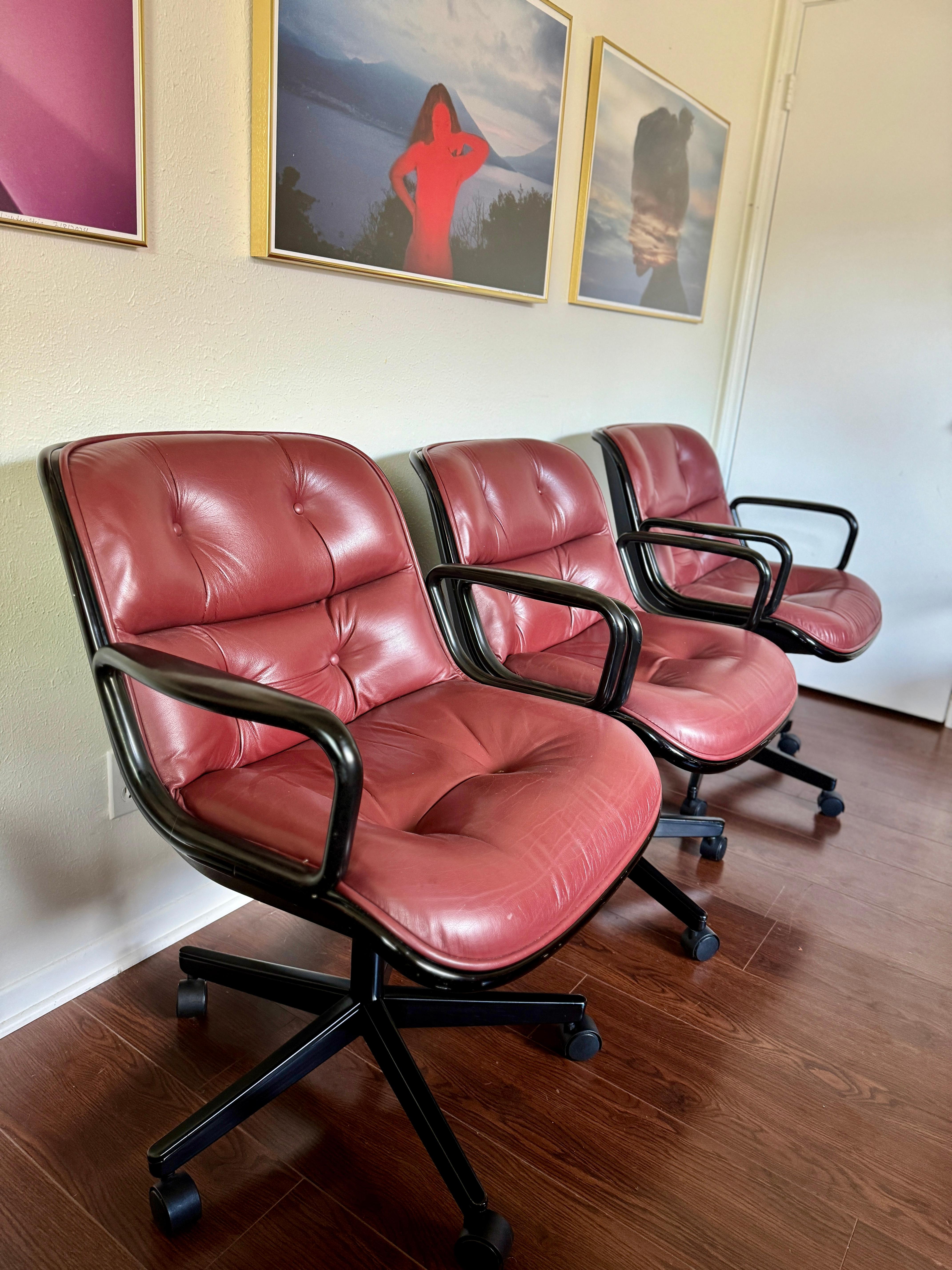 Buttery set of 3 executive armchairs designed by Charles Pollock for Knoll in 1956, in a rustic red leather upholstery with black arms on a 5 star swivel base with casters, tags still attached. Chair height is adjustable. Overall in good original