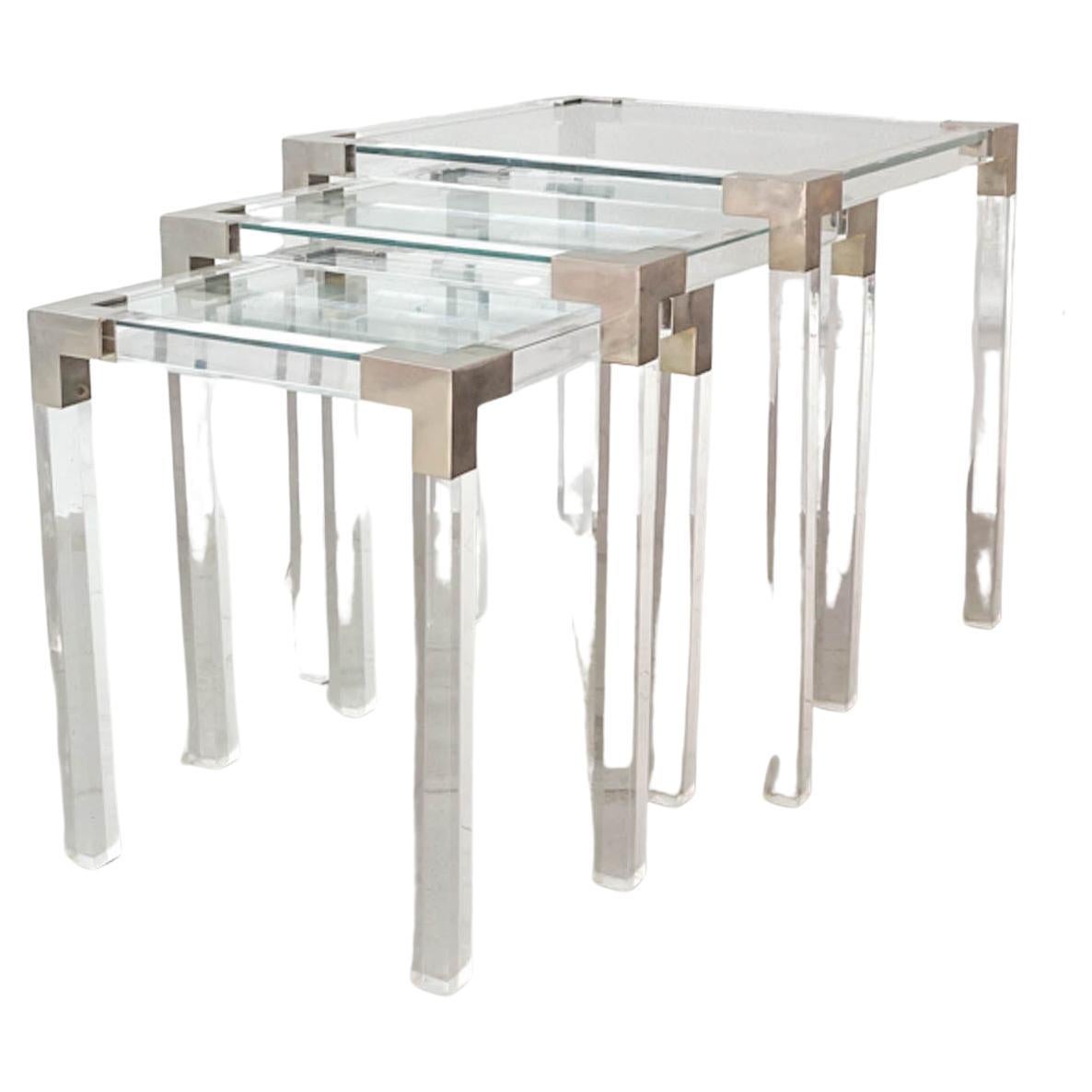 This set of 3 lucite nesting was designed and produced in the manner of Maison Jansen, in France during the 1970's. The structure of the tables is made of lucite and the corners are in brushed metal. The table tops are in clear glass. They are in