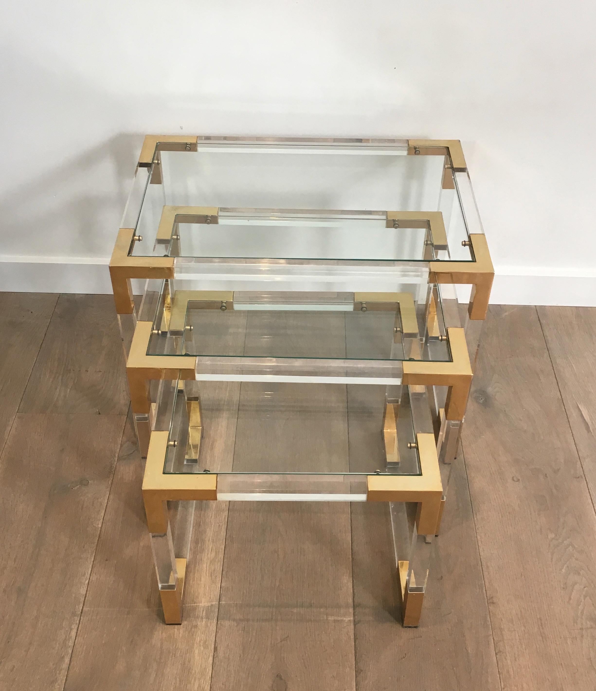 This set of 3 nesting tables is made of a Lucite base with gilt corners and glass shelves on top. These tables are very nice, simple and decorative and can be used individually, as side tables or even as a coffee table. This is a French work, in the