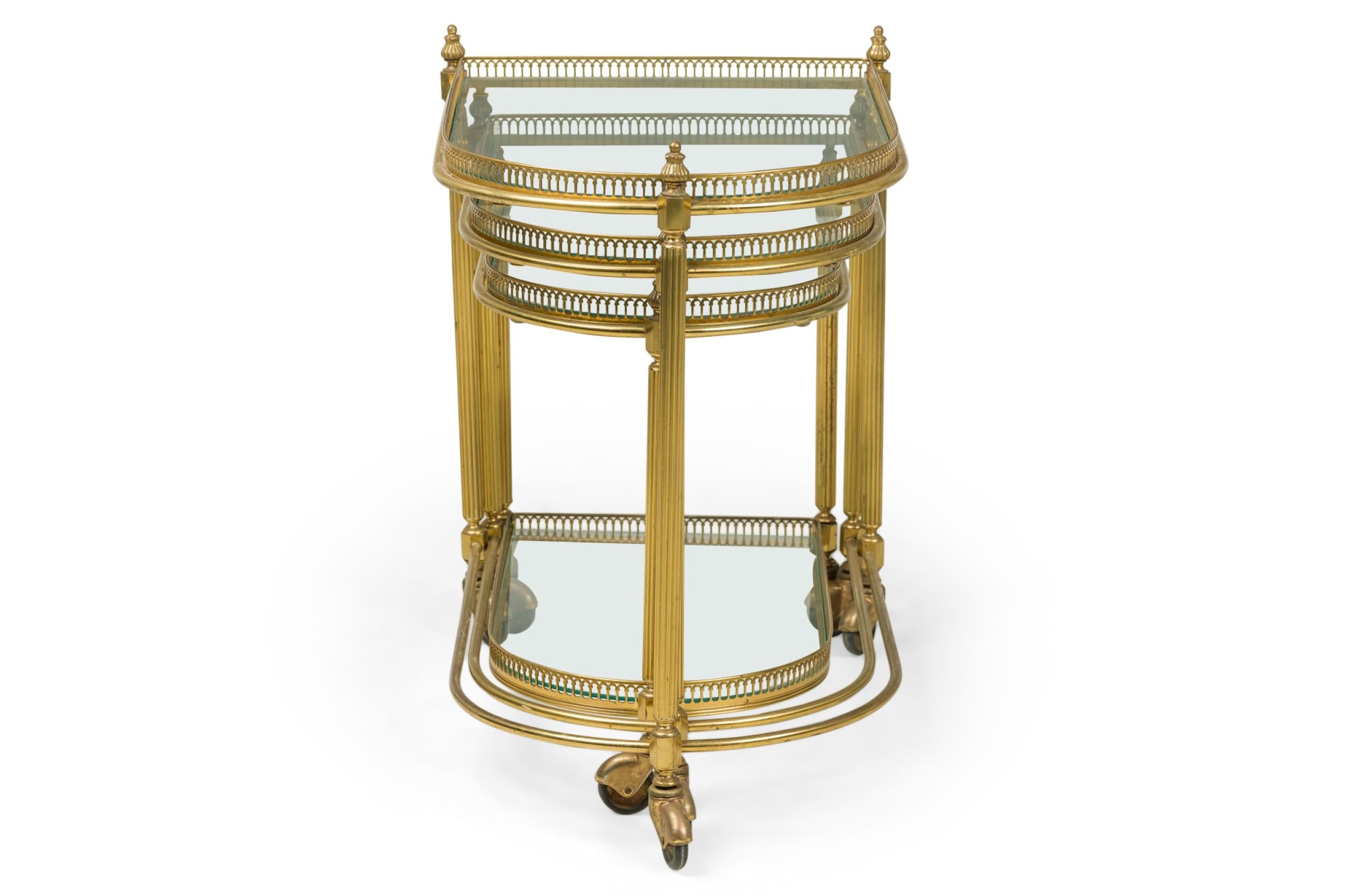 Set of 3 French Mid-Century rolling demilune nesting tables with brass frames having two shelves for demilune glass surrounded by a pierced low gallery, resting on three brass legs ending in small casters (MAISON JANSEN) (PRICED AS Set)

Some minor