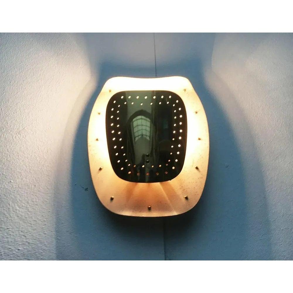 Appliques élégantes en blanc et laiton.

Les lampes sont divisées en deux parties : une plaque de support blanche et une façade en laiton attenante. La plaque de support est légèrement incurvée vers l'avant aux extrémités supérieure et inférieure.