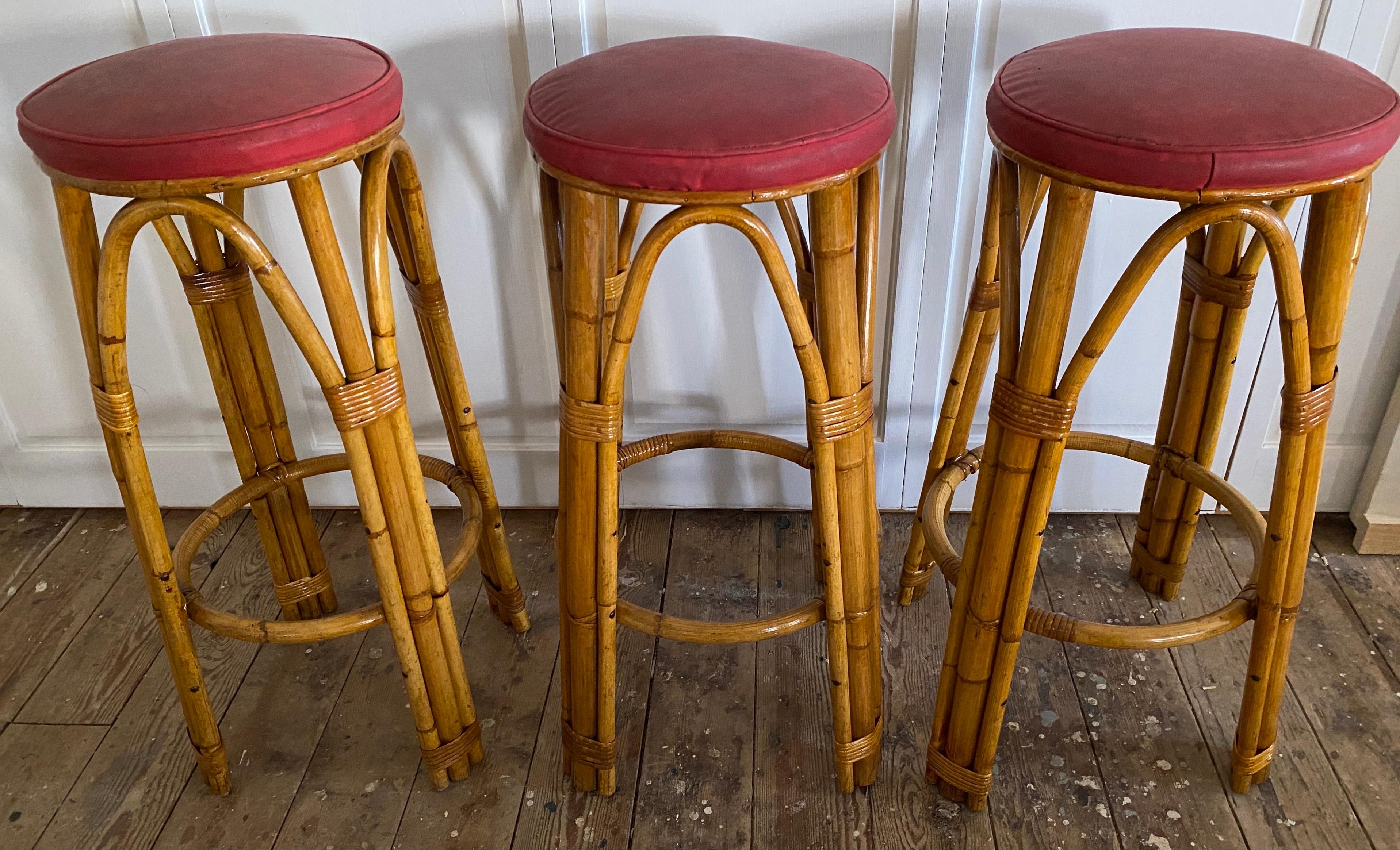 Set of 3 stylish deco style bamboo and caned vintage bar stools with vinyl padded seat cushions. Made in France in 1950s. The stools would be equally at home in a cafe bar, kitchen counter or breakfast bar.