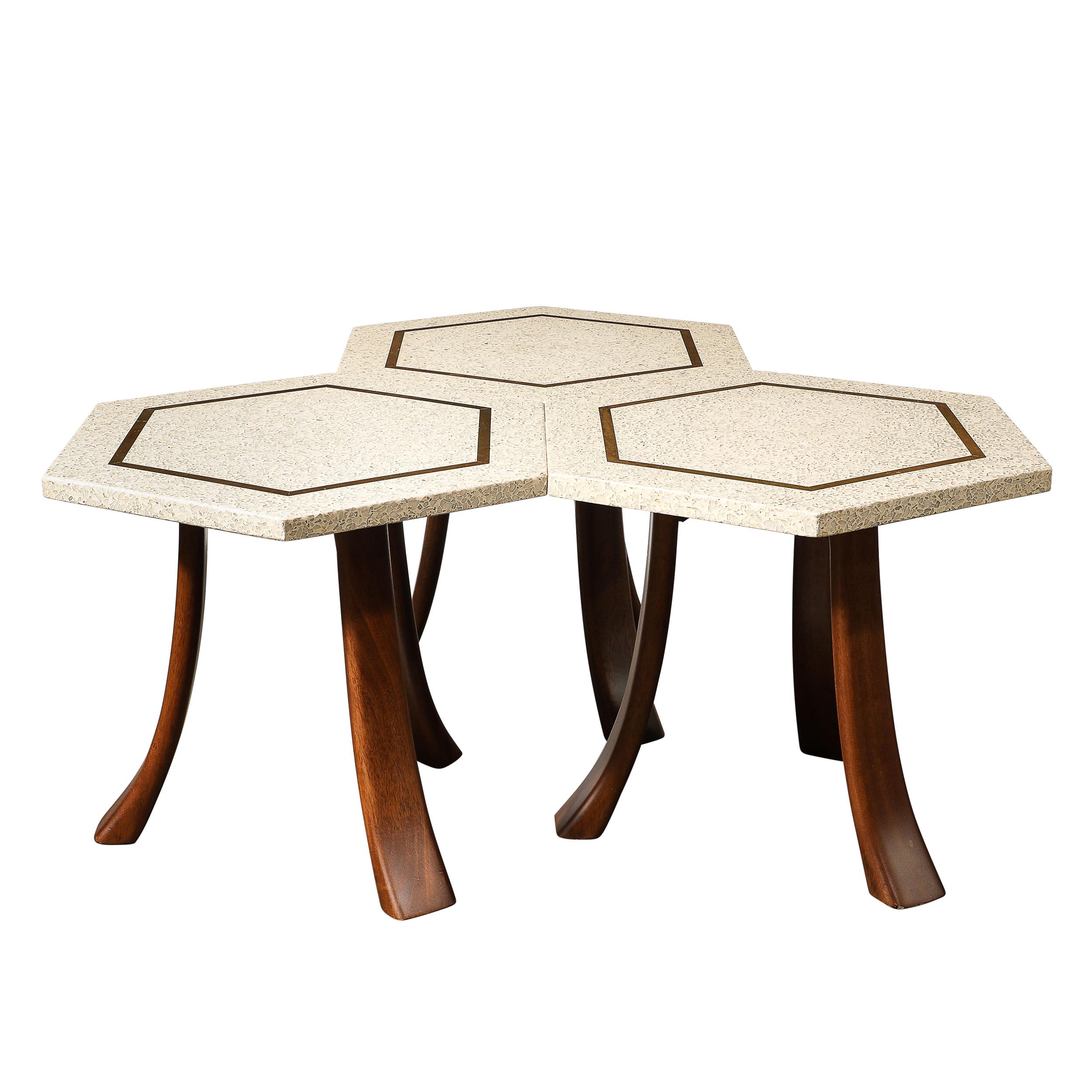 Cet ensemble unique de trois tables d'appoint hexagonales en terrazzo de style moderniste du milieu du siècle, avec incrustations en laiton et supports incurvés en noyer, par Harvey Probber, provient des États-Unis et date de 1950. Chaque table