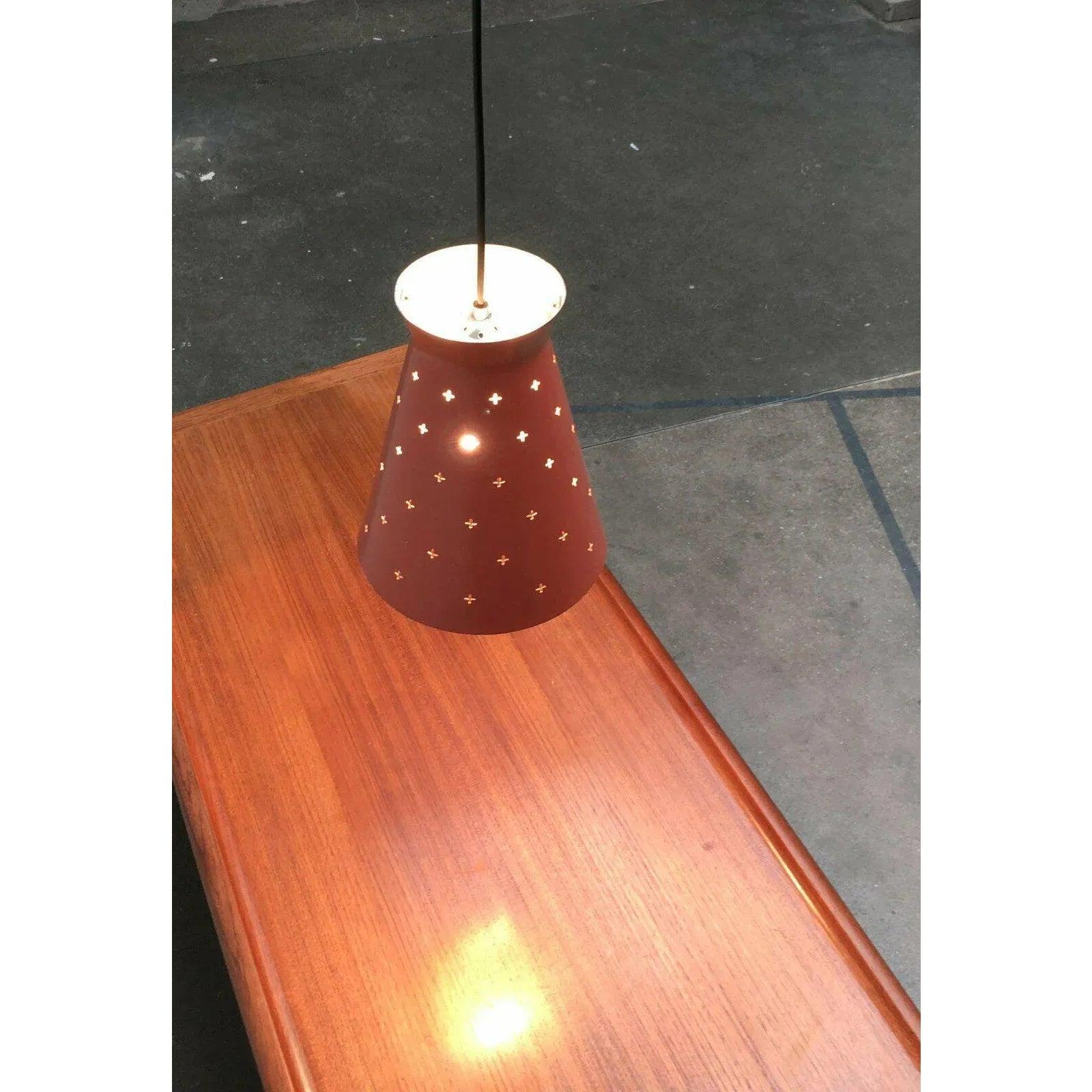 Lampada a sospensione di metà secolo con una suggestiva perforazione a croce. Il design è spesso attribuito al produttore italiano Stilnovo. Probabilmente è di origine tedesca e proviene da Hillebrand.

L'ombrello ha una semplice forma a diabolo. La