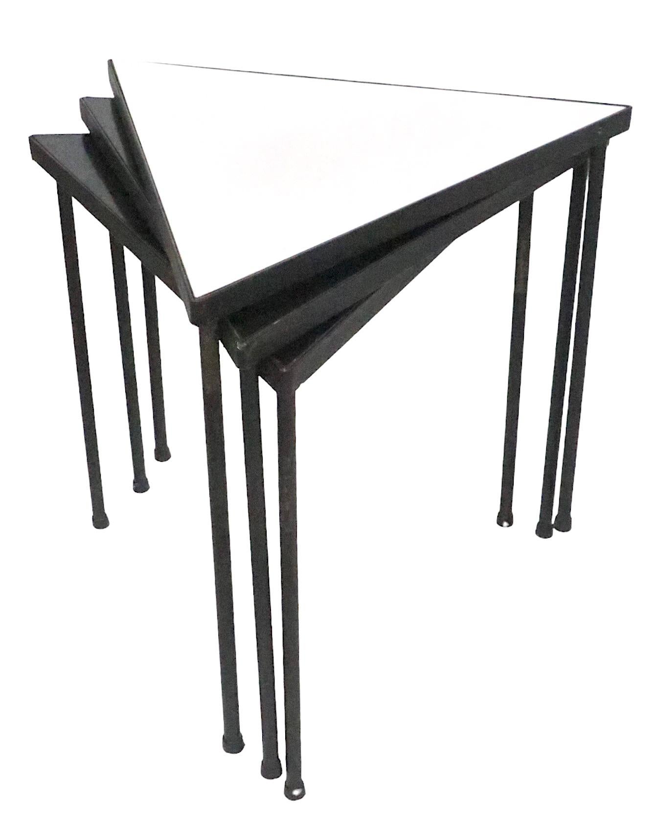 Set of three mid century triangular stacking tables, designed by Frederic Weinberg circa 1950's. The set consists of two black top  and one white top tables, which can be used individually as side, end or serving tables, or placed together to create