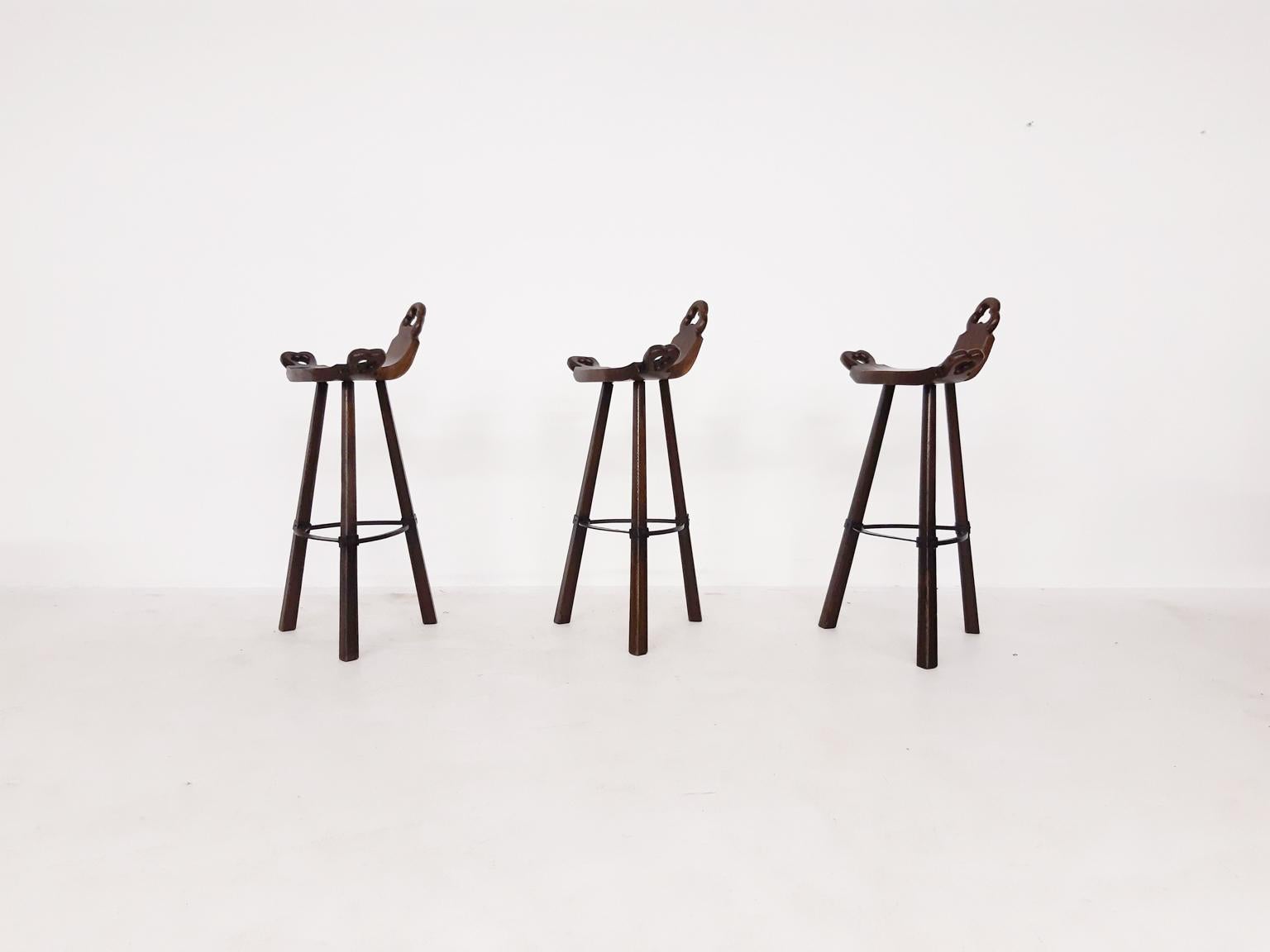 Set of 3 midcentury Brutalist Spanish bar stools. 

Made of wood with a metal footrest.

In good vintage condition.