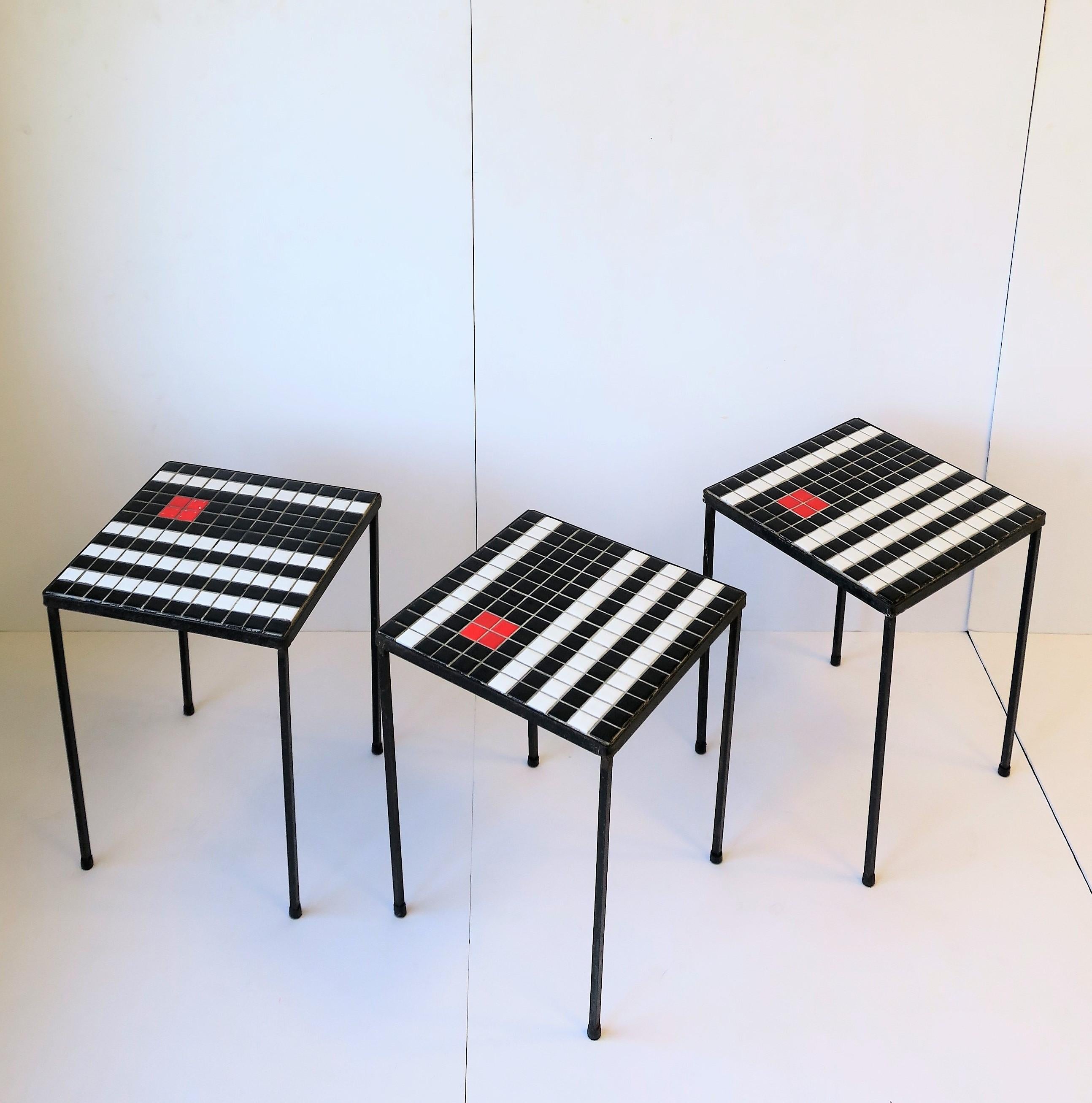 A set 3 of Mid-Century Modern small square black and white, and a touch of red, mosaic tile stacking, side, or drinks tables, circa mid-20th century. Tables are wrought iron frames with ceramic tile tops. Tables offer a great look with 'Minimalist'