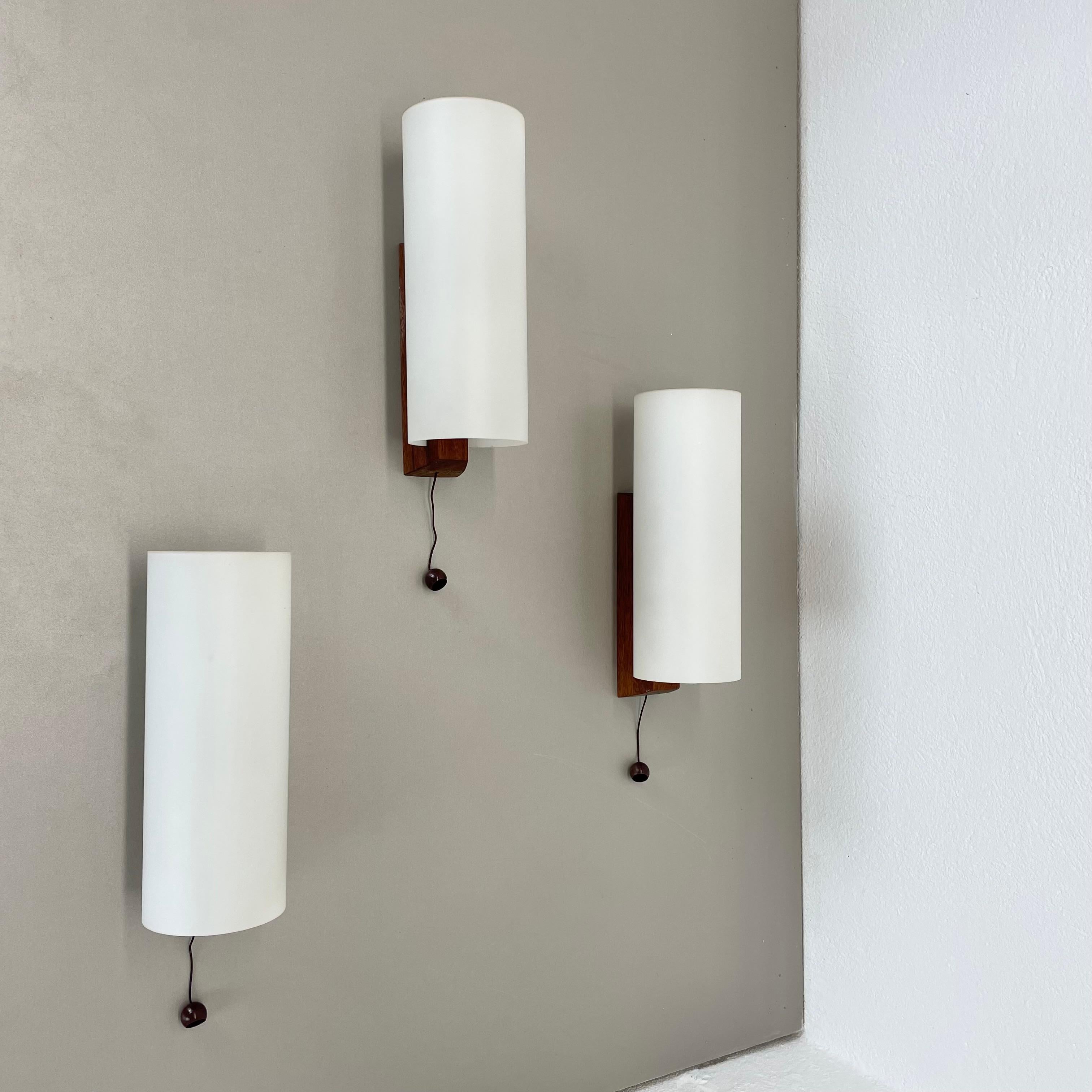 Article:

wall light set of 3


Origin:

Denmark


Age:

1960s




This modernist wall light set was produced in DENMARK in the 1960s. The light has solid teak wood wall fixation and large satin white glass stacking element at the front. Due to the