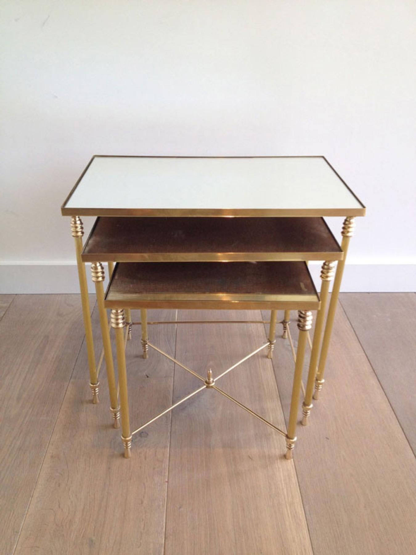 This nice set of 3 neoclassical style nesting tables is made of brass with mirror tops. This is a French work, in the style of famous designer Maison Jansen. Circa 1940.