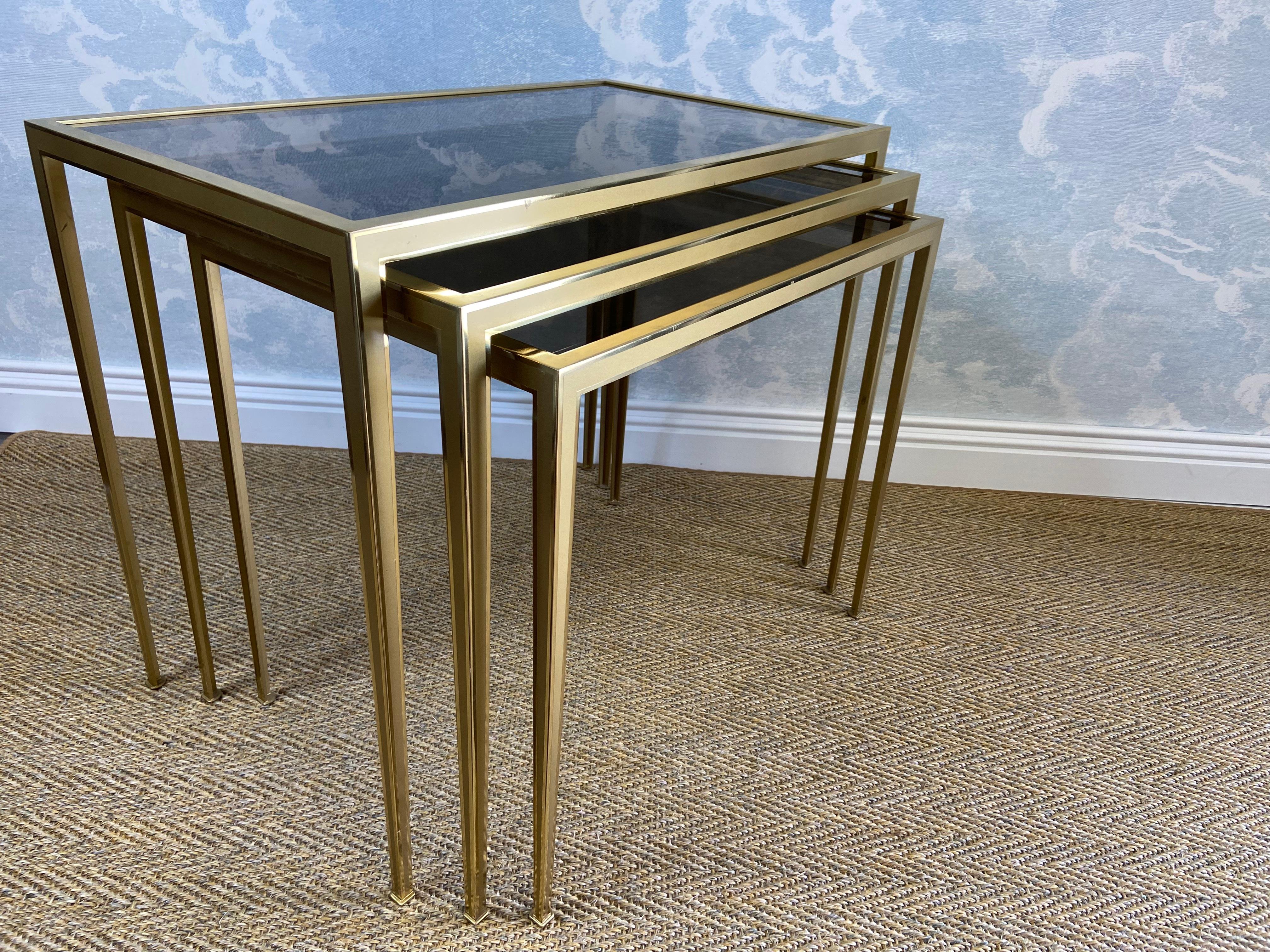 This elegant ensemble of three nesting tables was manufactured by Vereinigte Werkstätten in Munich in the 1960s and is in great condition.

Set on narrow ending legs, the bi-color brass frames have a polished and brushed finish and support the brown