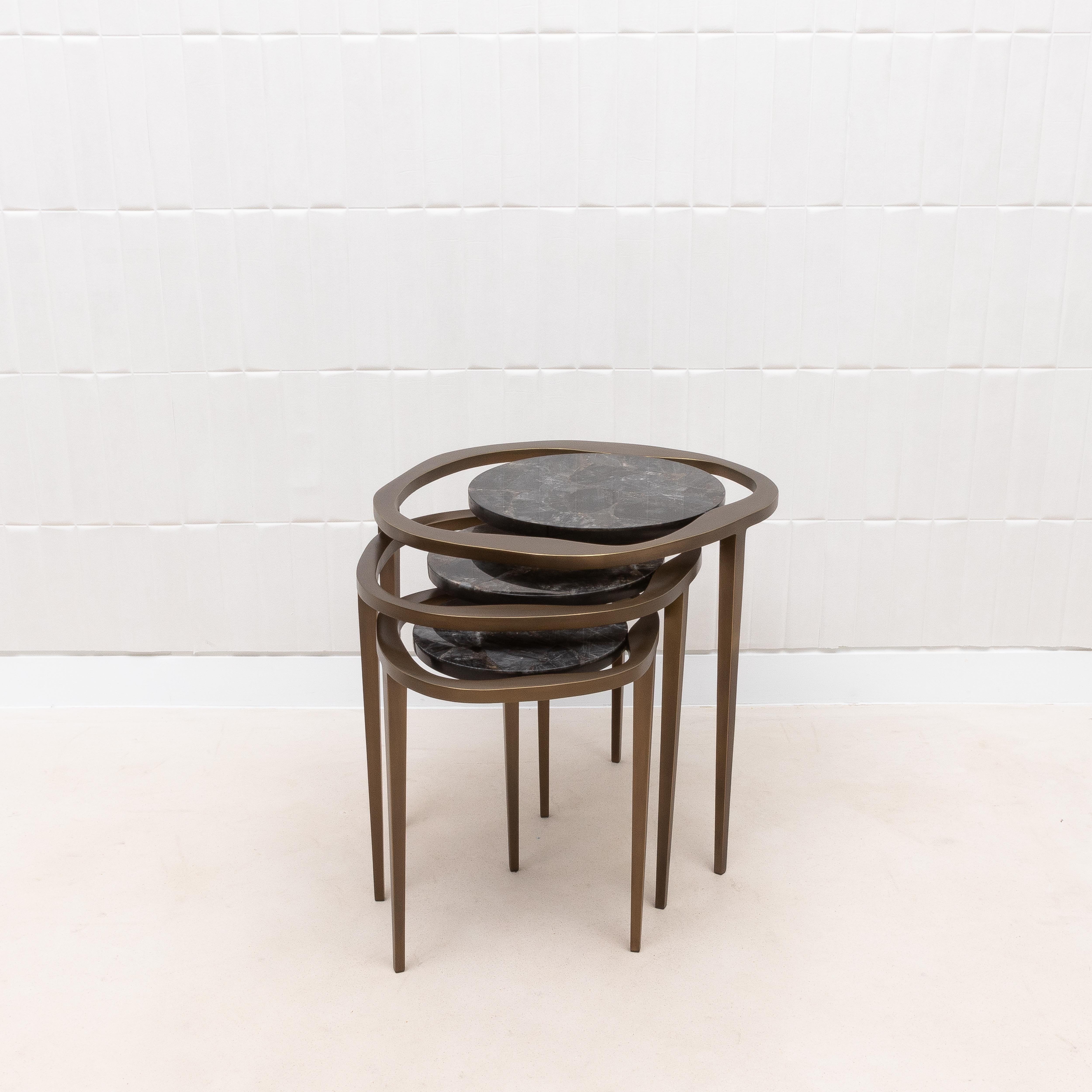 Experimenta el refinado encanto de las Mesas nido Lily de R&Y Augousti, donde la riqueza del cuarzo negro se une a los sofisticados tonos del latón patinado en bronce. Este conjunto de tres mesas, con su forma escultural inspirada en la delicada