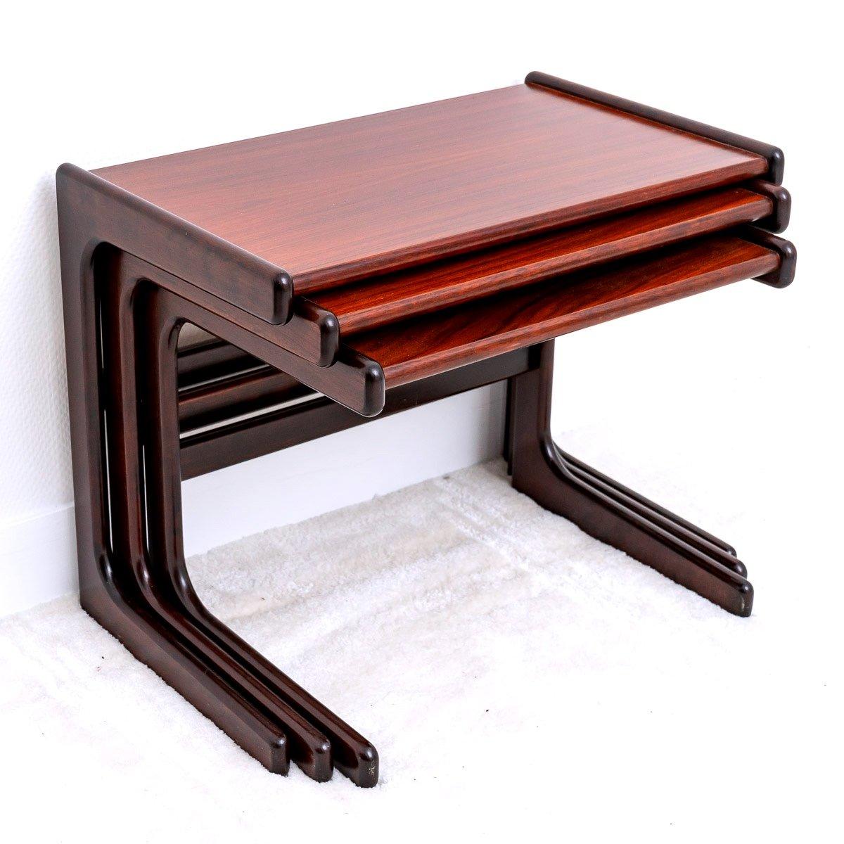 Beautiful modern set of three nesting tables in rosewood. The legs are in solid rosewood and the tops in rosewood veneer.

The tables have the shape of the letter 