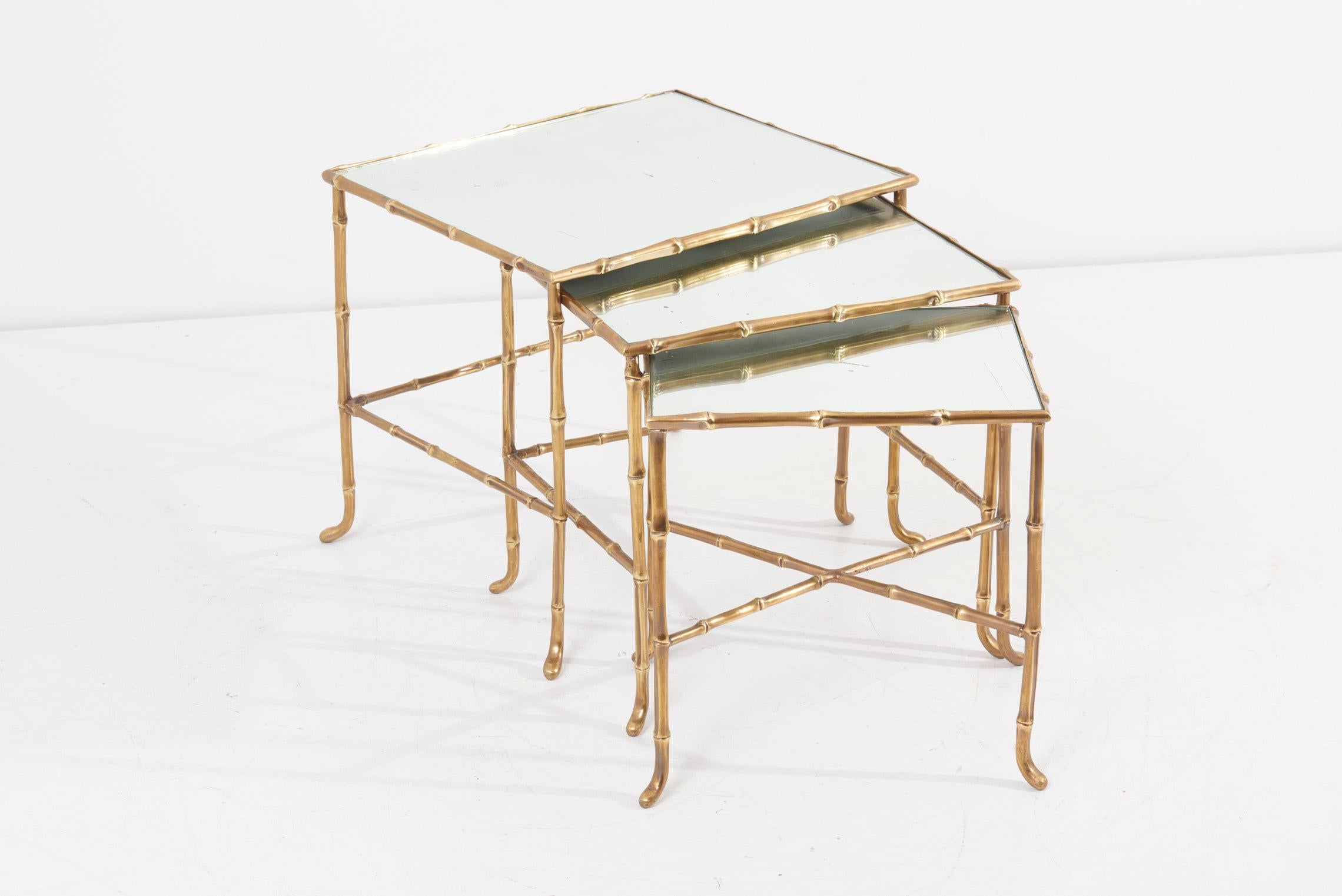 Set of three nesting tables in bamboo shape by Maison Baguès in France. Made of brass and with mirror tops. The measurements given apply to the smallest table. 

Measurements table large: D 51.5 cm, W 41.5 cm, H 44.5 cm 
Measurements table