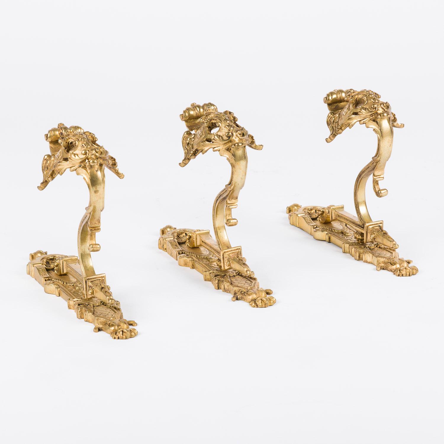 A set of three late 19th century French very ornate gilt bronze curtain hooks in the Louis XV style.

Foundry Mark: GH

Projection from wall: 7 inches.