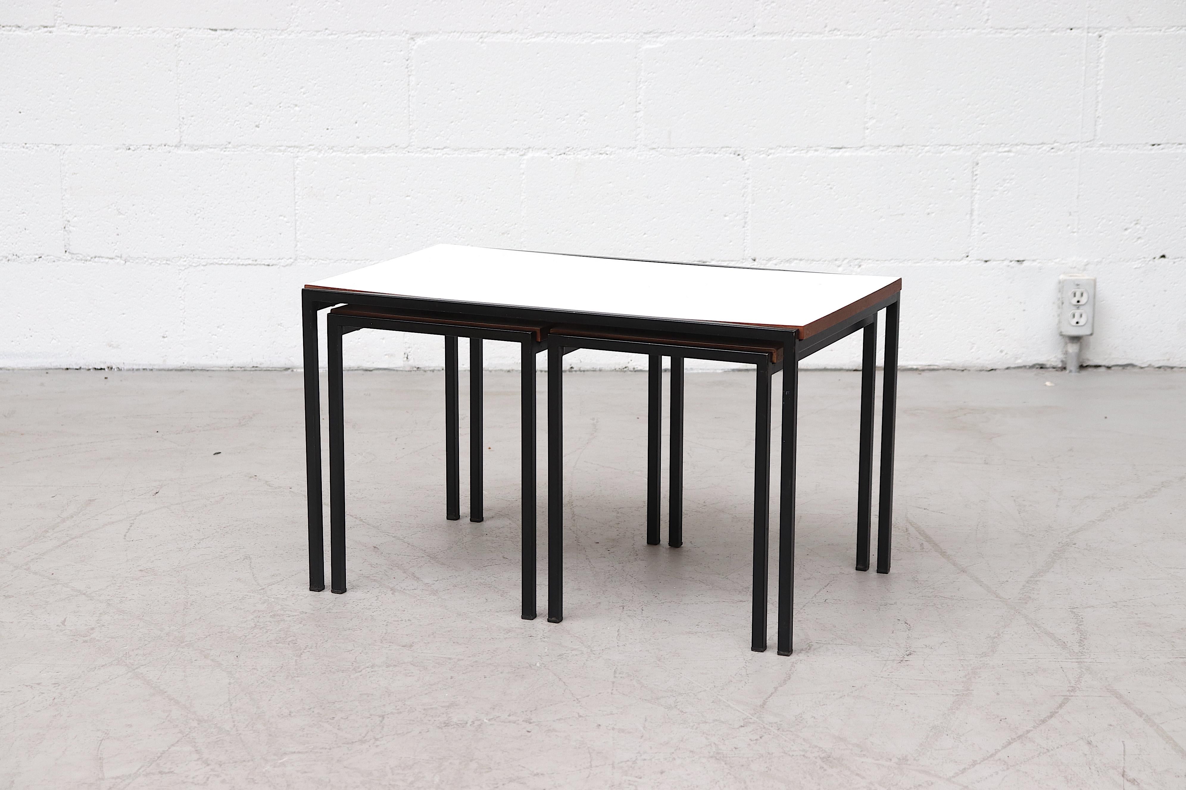 Amazing set of 3 Pastoe nesting tables with Formica tops, teak edging and black enameled metal frames. In original condition with visible wear and original manufacturer sticker. Set price.