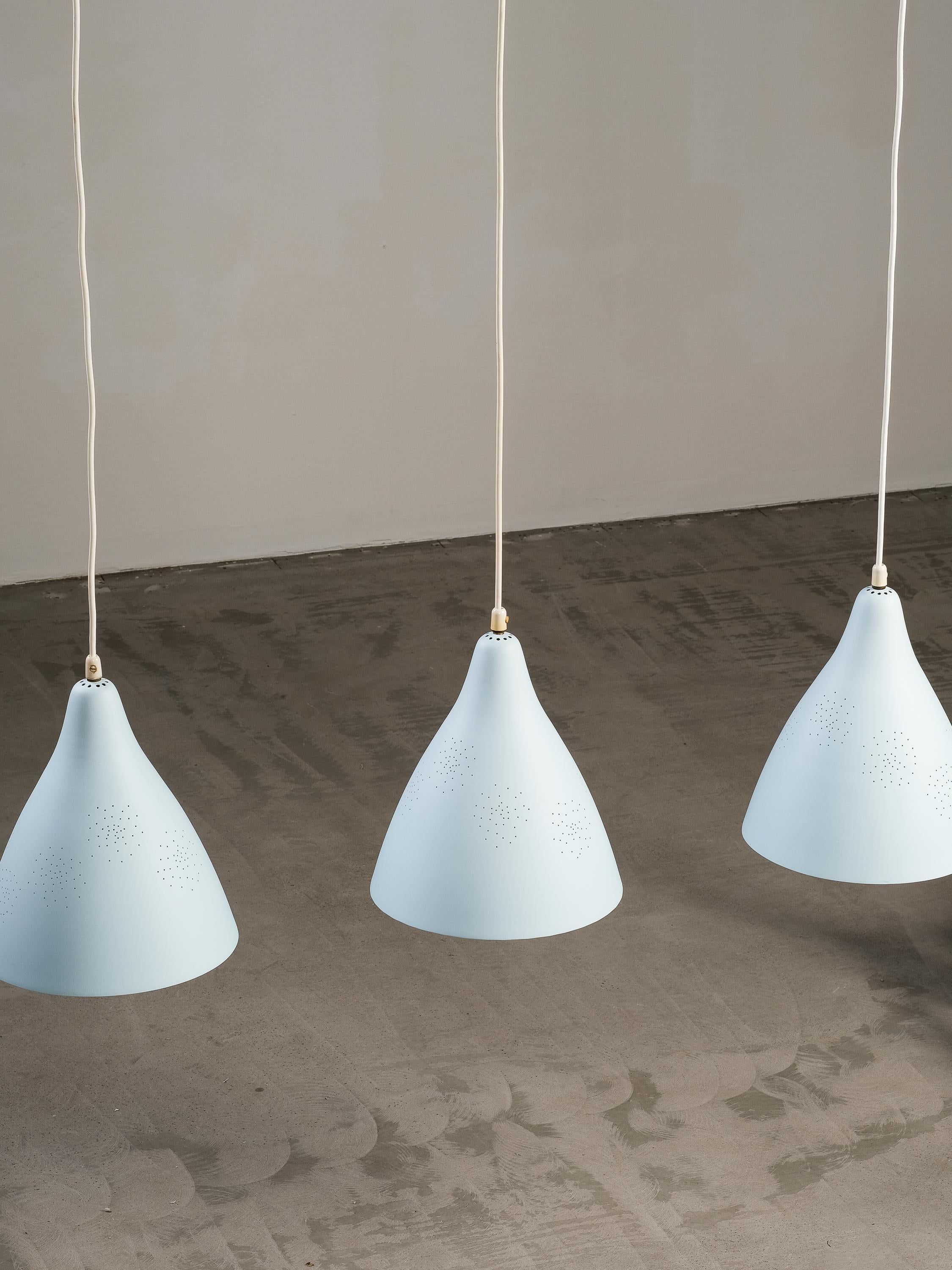 A very beautiful set of 3 pendant lamps, model 61-314 designed by Lisa Johansson-Pape, and manufactured by Orno in the 1950s. Perforated shade full of tiny dots in her circular pattern that form a lovely design across the lamp.

The lamps are very