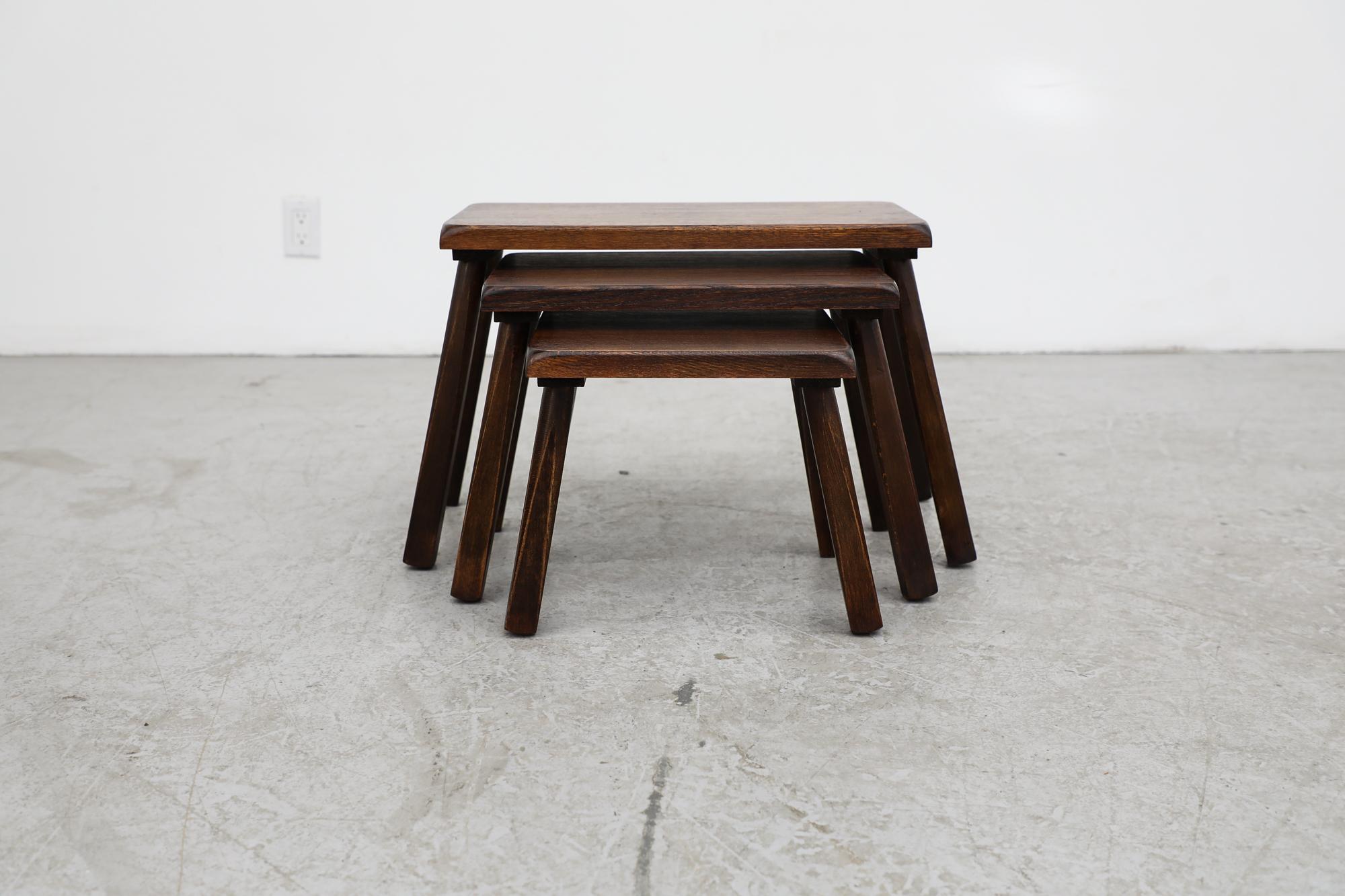 Set of 3 dark stained Brutalist nesting tables inspired by Pierre Chapo with round tapered legs. All lightly refinished and in otherwise original condition. The middle table measures 20.25 x 12.5 x 13.5 and the smallest table measures 15.25 x 12.5 x