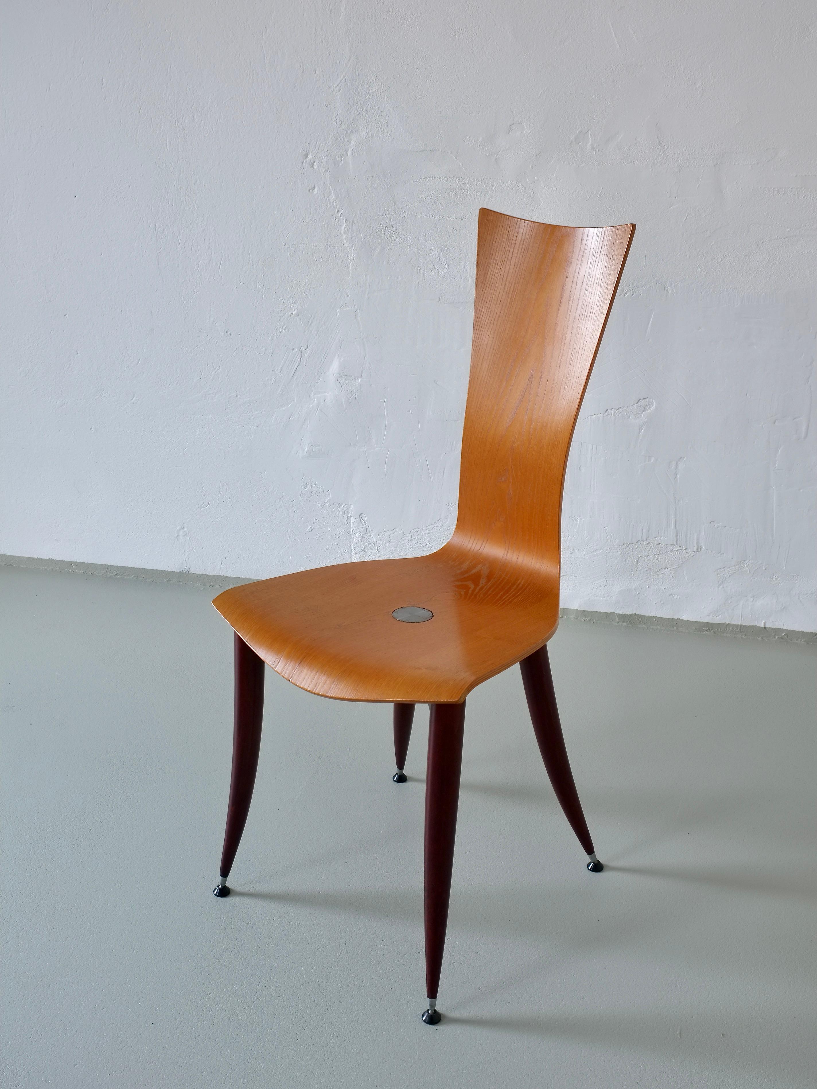 A set of three vintage plywood chairs featuring burgundy-red legs, designed in the style of Philippe Starck or Umberto Mascagni. 