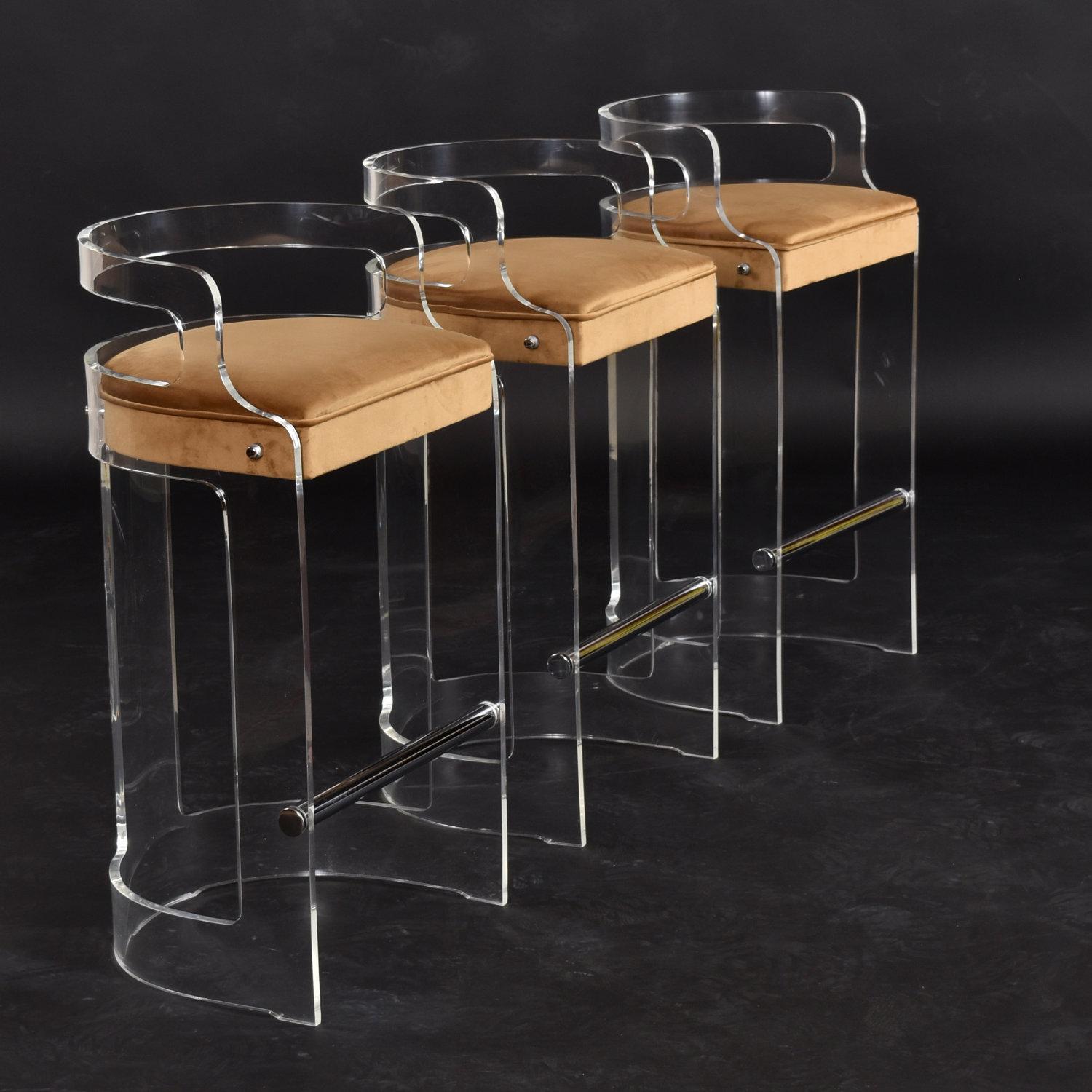 Set of three vintage 1970s Post Modern clear acrylic bar stools. The chic Lucite bar stools are restored with new luxurious gold velvet upholstery on the seats. Our restoration team has hand buffed the vintage acrylic. The thick Lucite frames have a