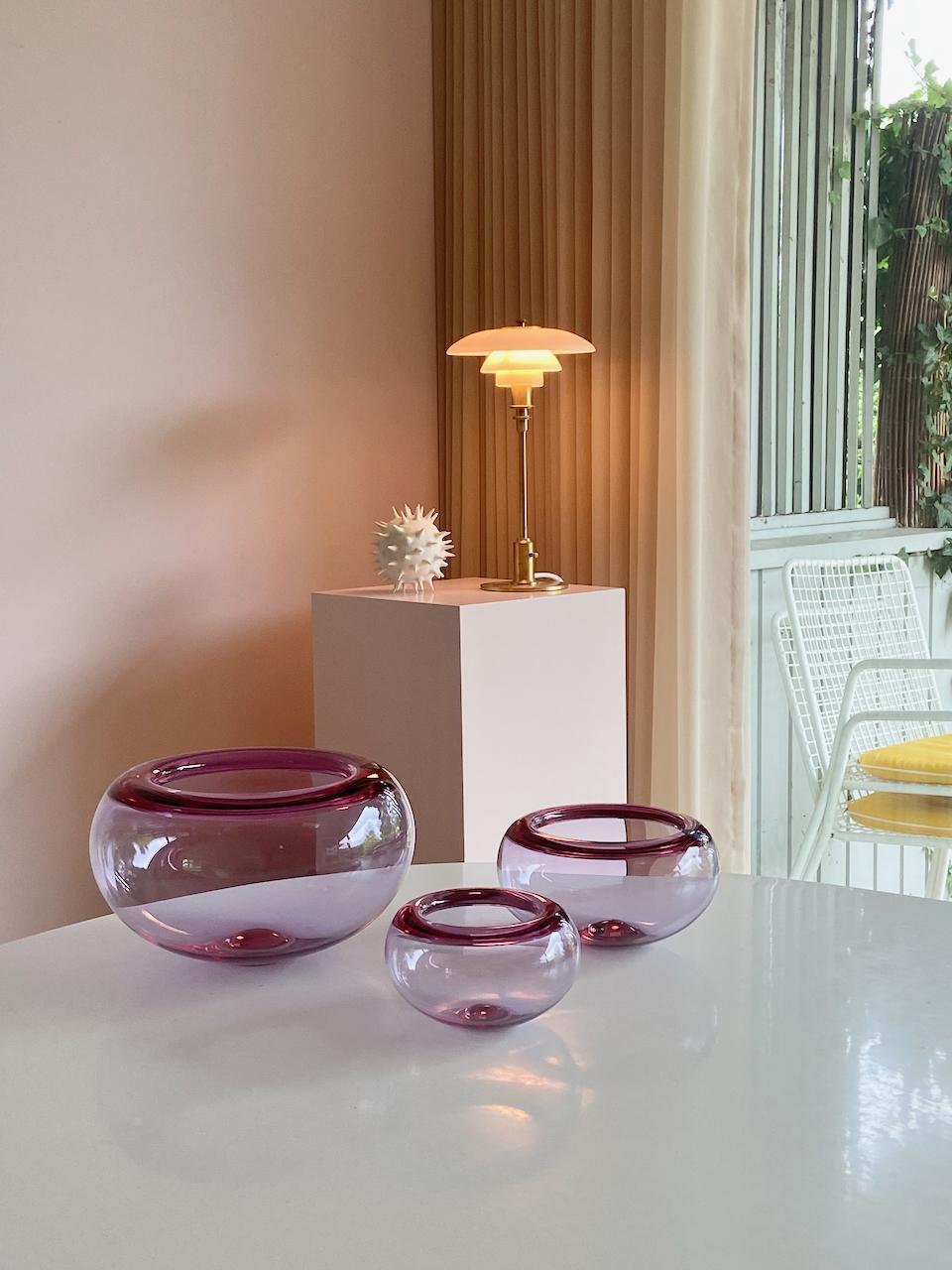 Set di 3 ciotole in vetro soffiato a mano di colore viola chiaro, disegnate da Per Lütken e prodotte da Royal Copenhagen in Danimarca. 
Dimensioni: diametro 28cm e altezza 15cm / d.18cm e h.10cm / d.14cm e h.8cm
Prezzo per il set di tre, per la