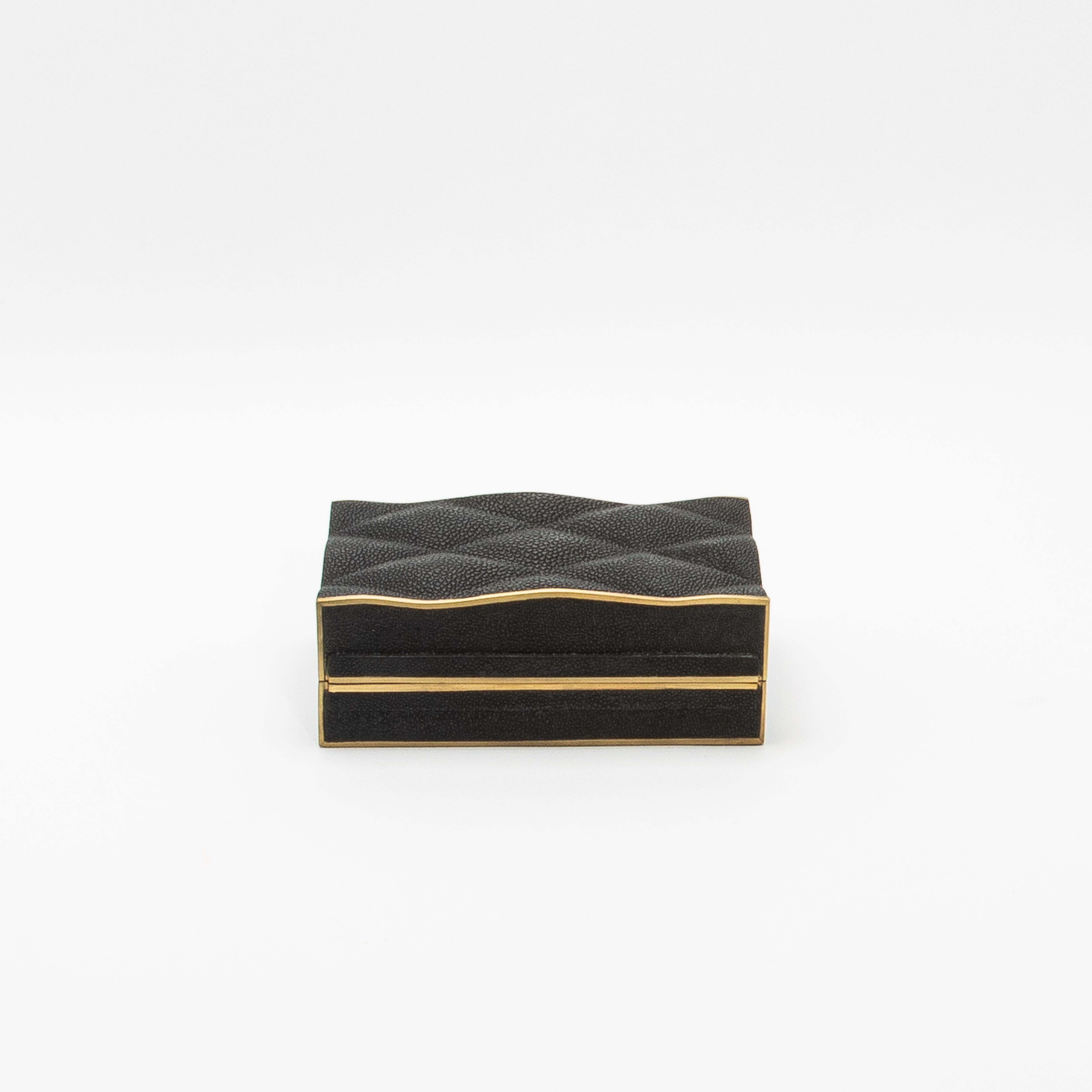 La colección de cajas Coco de Kifu Paris ejemplifica el lujo a través de su intrincado diseño y su meticulosa artesanía. Este conjunto de tres cajas acolchadas en piel de zapa negra, enmarcadas con un borde de latón patinado en bronce, irradia