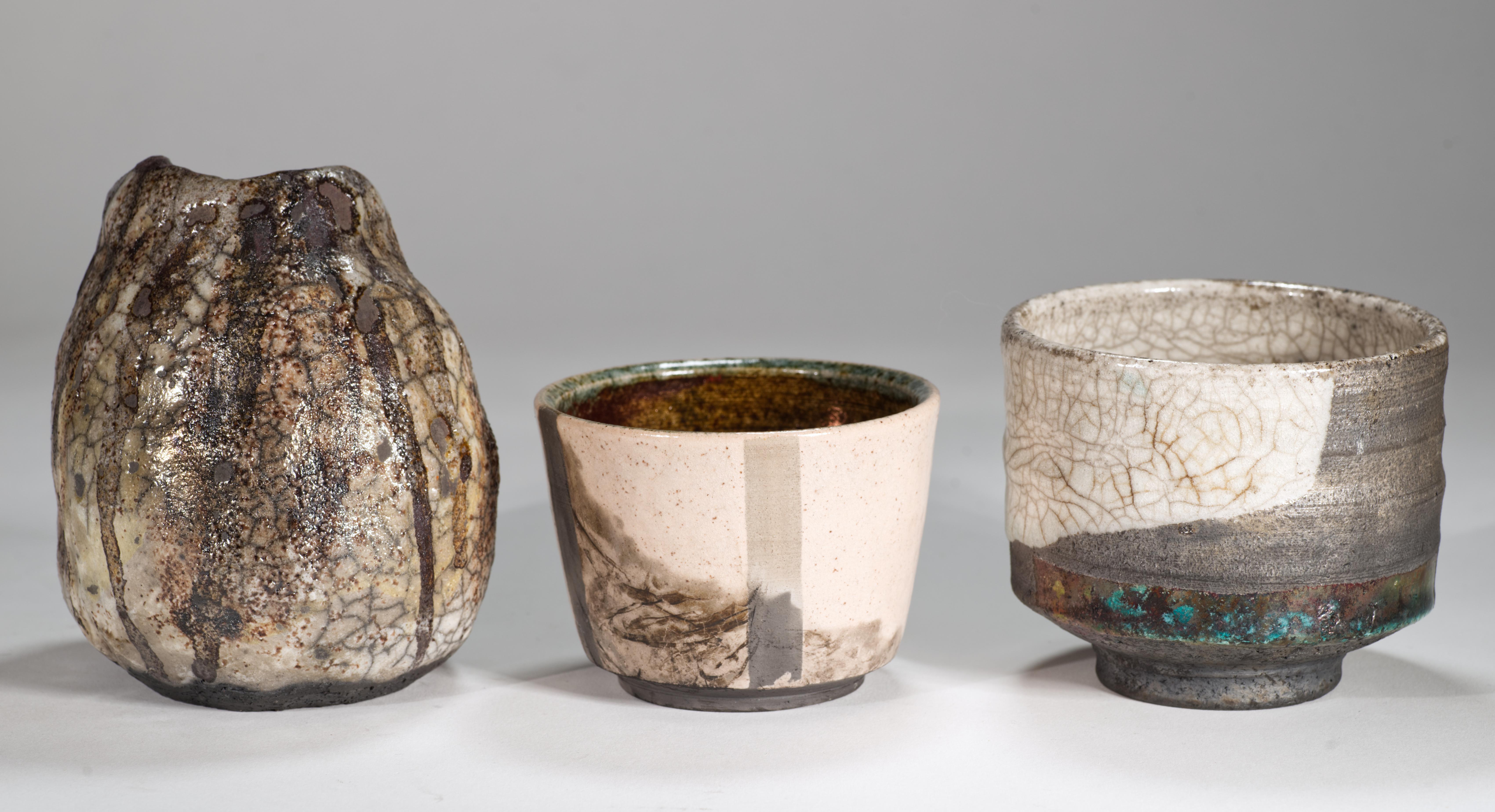 Il set di 3 vasi scultorei in ceramica presenta una finitura Raku metallizzata multicolore e smalti craquelure con toni predominanti di grigio, marrone e bianco sporco. Gli smalti complessi e grafici completano la forma minimale dei vasi, guidando