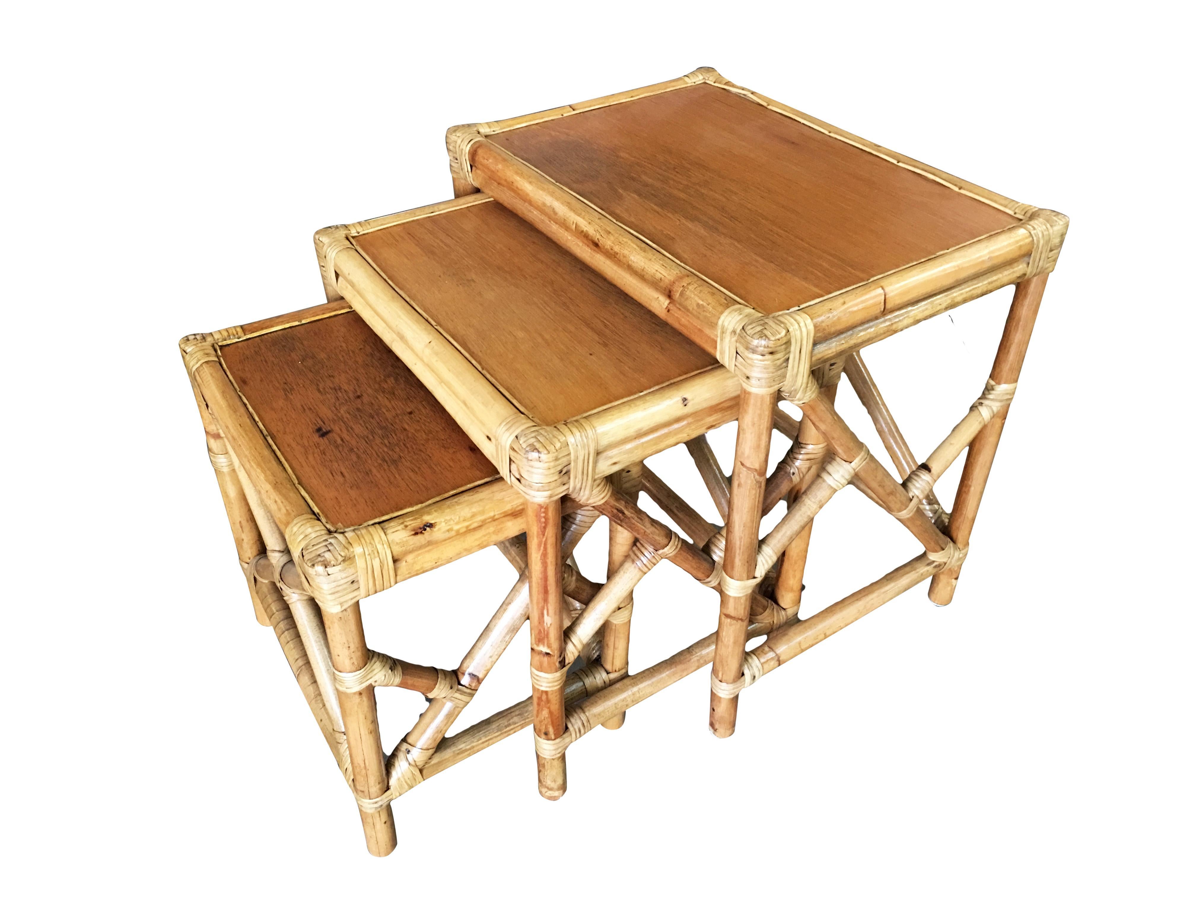 A wonderful set of 3 rattan nesting tables with inset mahogany table tops and fancy wrappings. The rattan used for these nesting tables was imported from the Philippines and assembled in the United States, as is typical of high-end Rattan of the