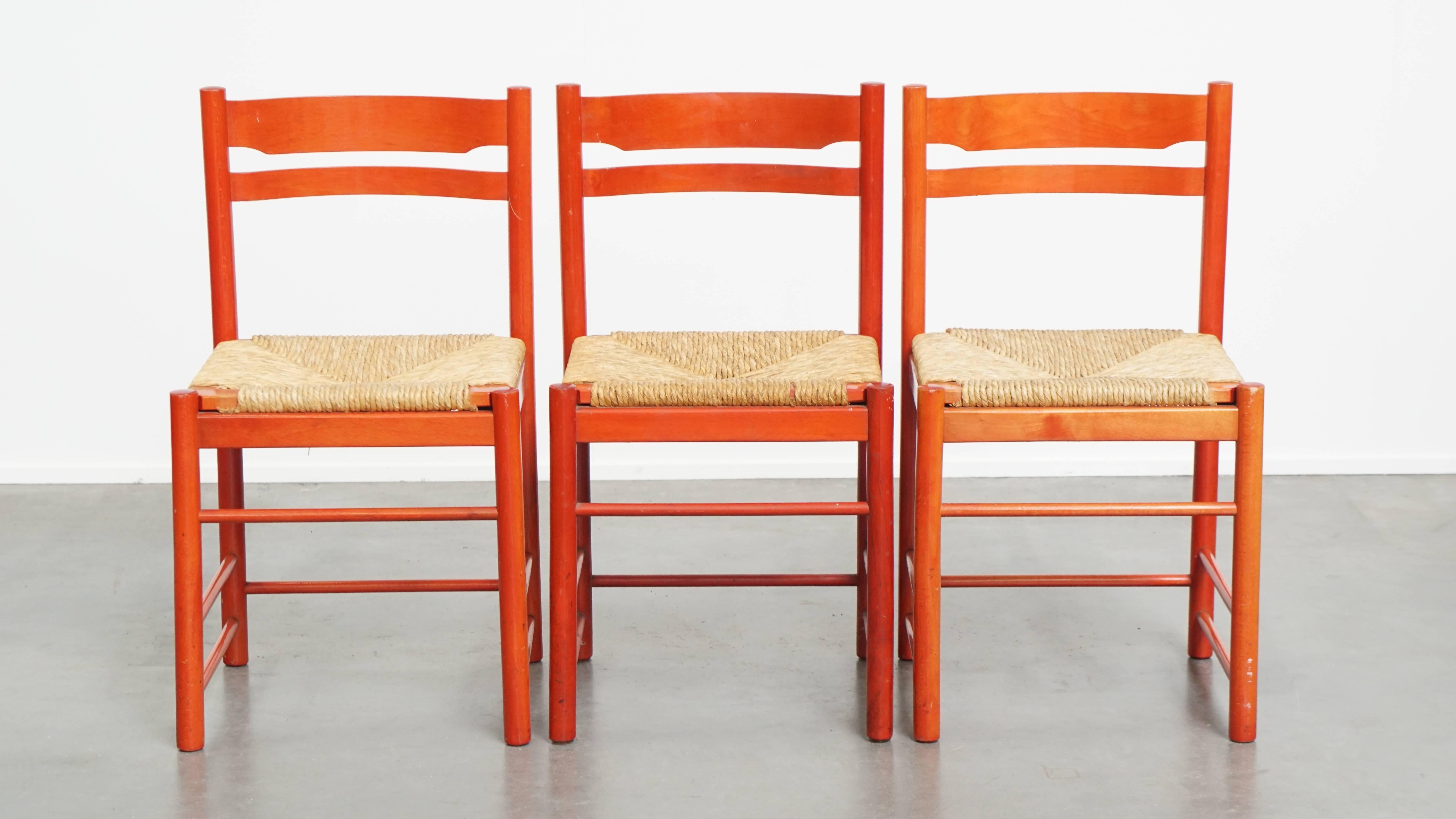 Offered: this lovely set of three vintage red wooden chairs from the 1970s with a wicker seat.

This lovely set of three vintage red chairs has a wooden frame and a wicker seat. They are easy to place in almost any interior. The chairs have normal