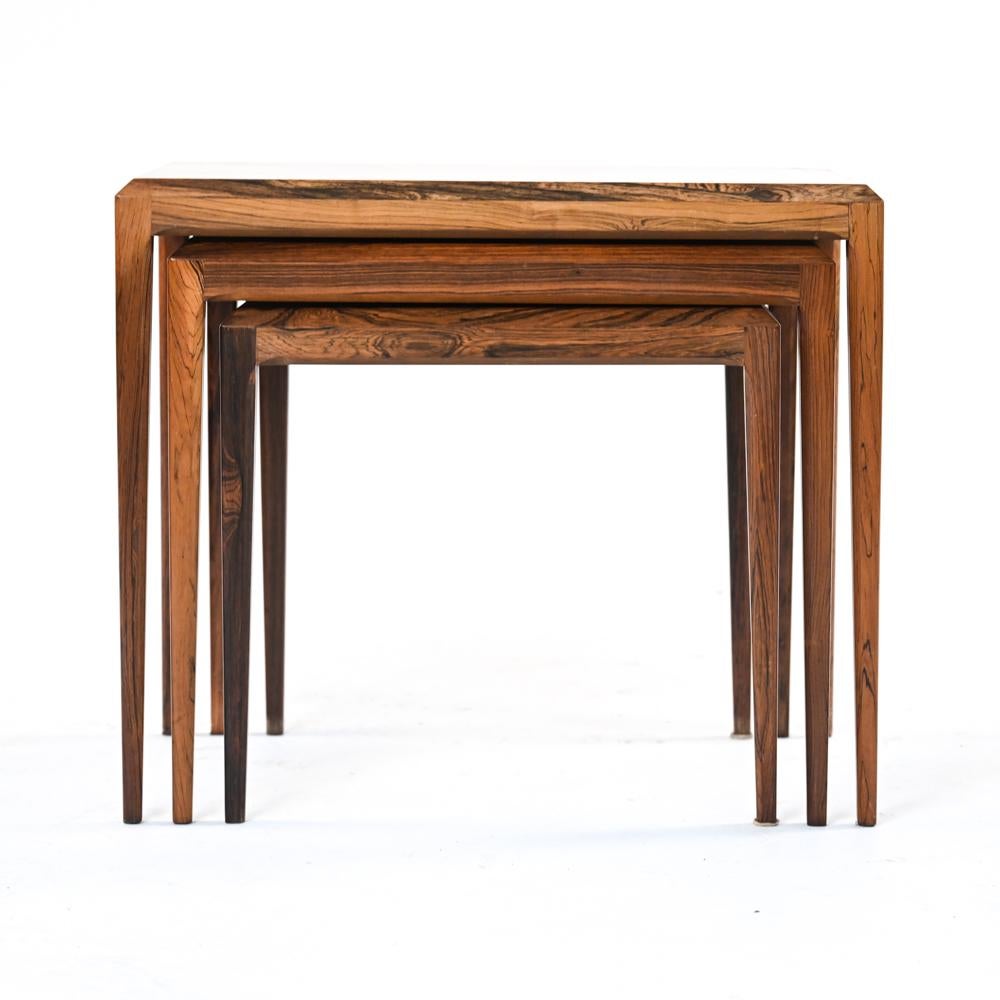 Bel ensemble de (3) tables gigognes en bois de rose, avec d'élégants pieds coniques et des plateaux biseautés, typiques des œuvres du designer Johannes Andersen. Circa 1960's, marqué avec des restes d'étiquette en dessous.