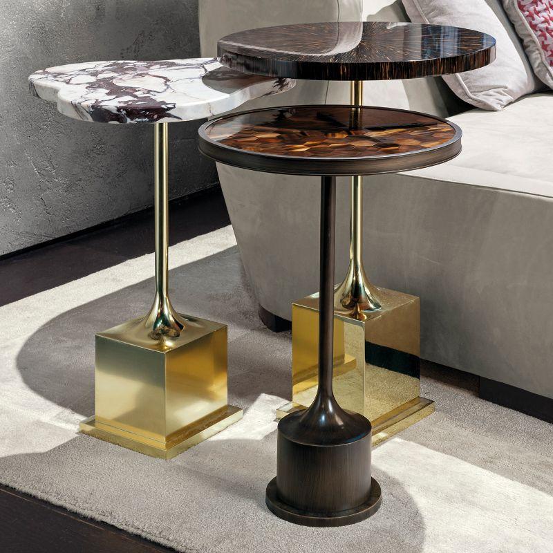 A stately set of three side tables to enrich both classic and modern interiors with sophisticated allure, these three stupendous artworks are deftly handcrafted of precious materials. Resting on polished, bronze, or matte brass legs, the top is