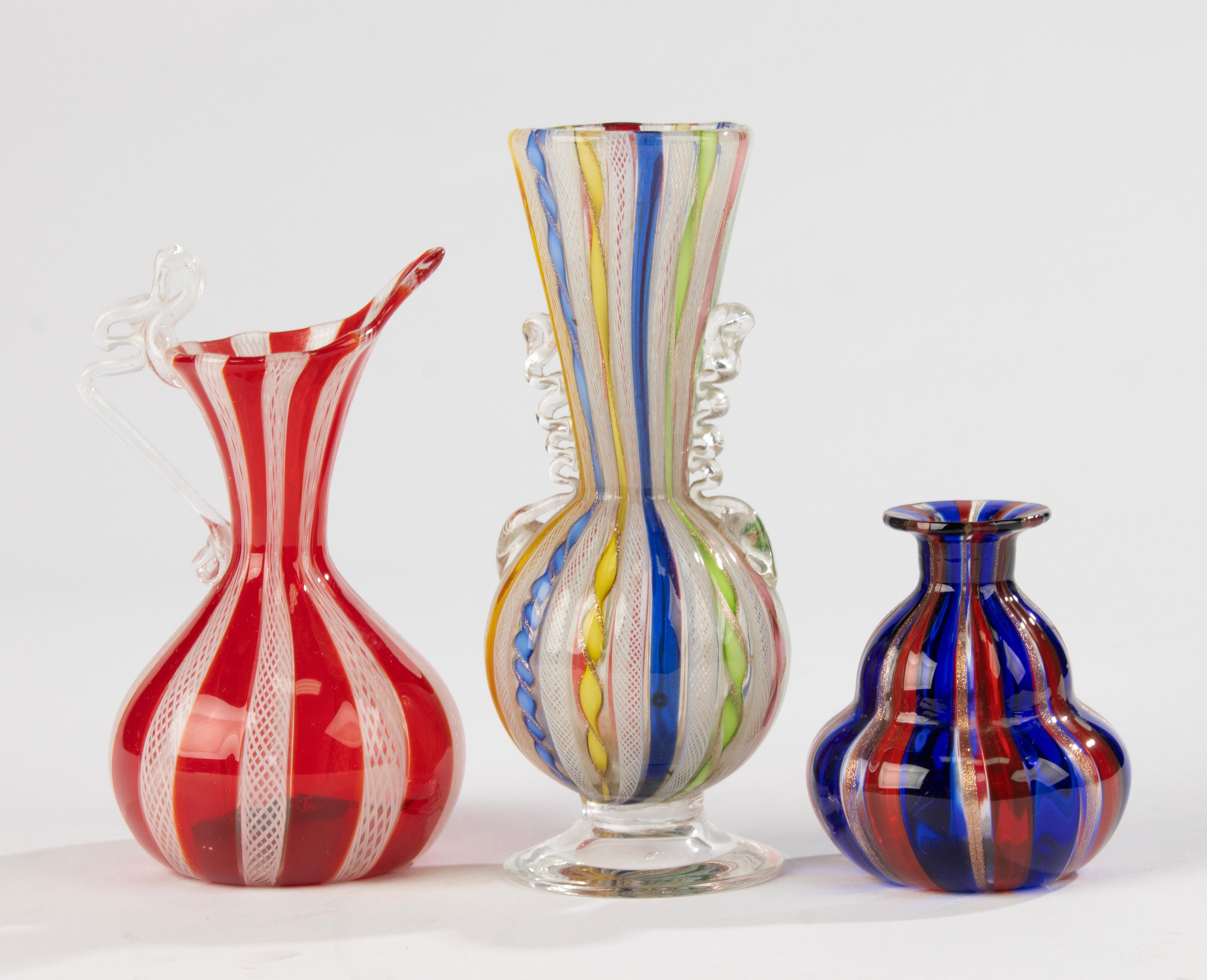 A charming trio of petite hand-blown Murano glass vases, crafted in Italy in the mid-20th century. Each vase features bold, colorful stripes in traditional canne and filigrana techniques, making them miniature statements of Venetian glass