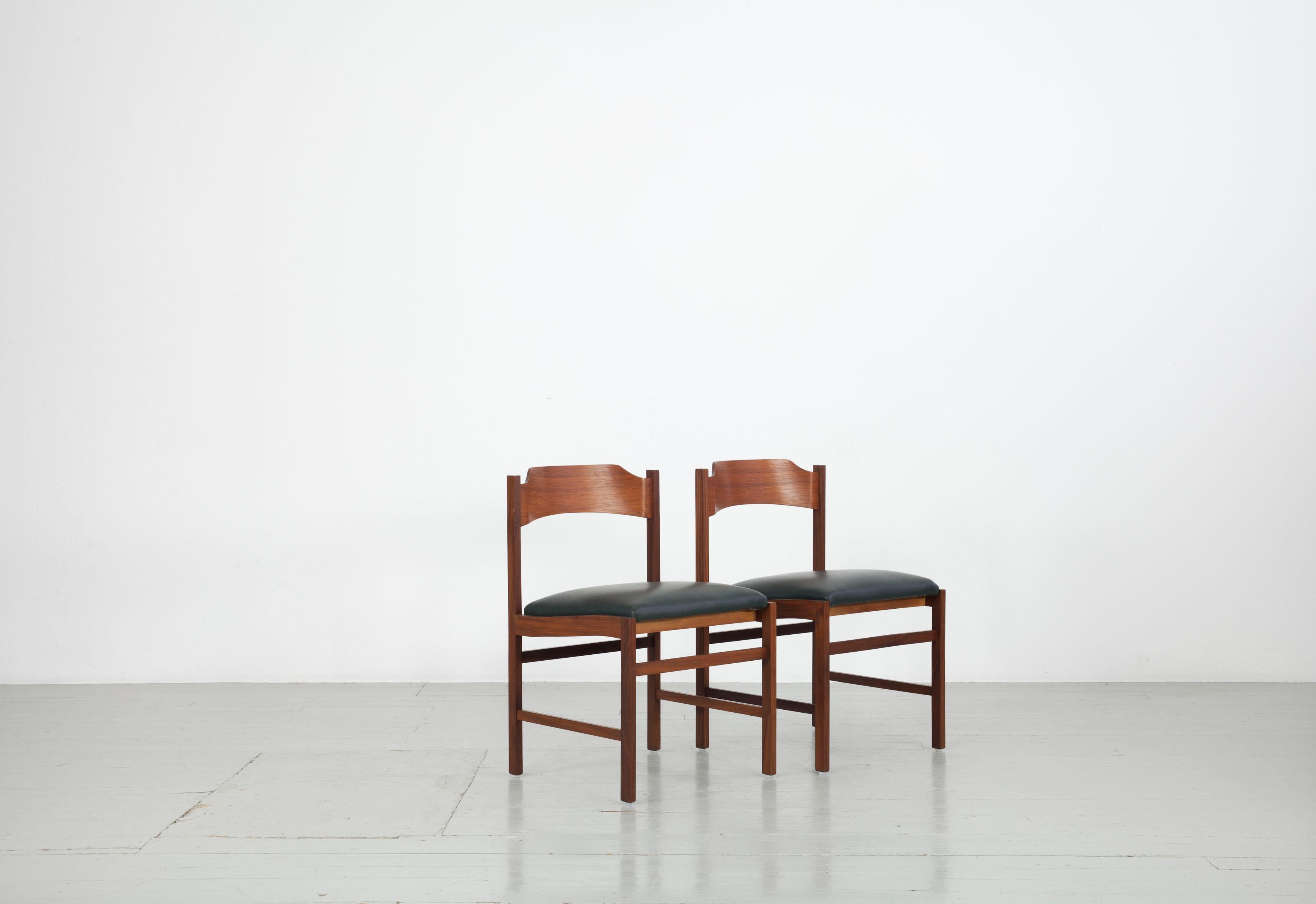 Cet ensemble de deux chaises en bois a été fabriqué en Italie dans les années 1960. La structure est en placage de noyer, l'assise et le dossier sont recouverts de similicuir vert foncé. Les deux chaises sont en très bon état vintage.

 