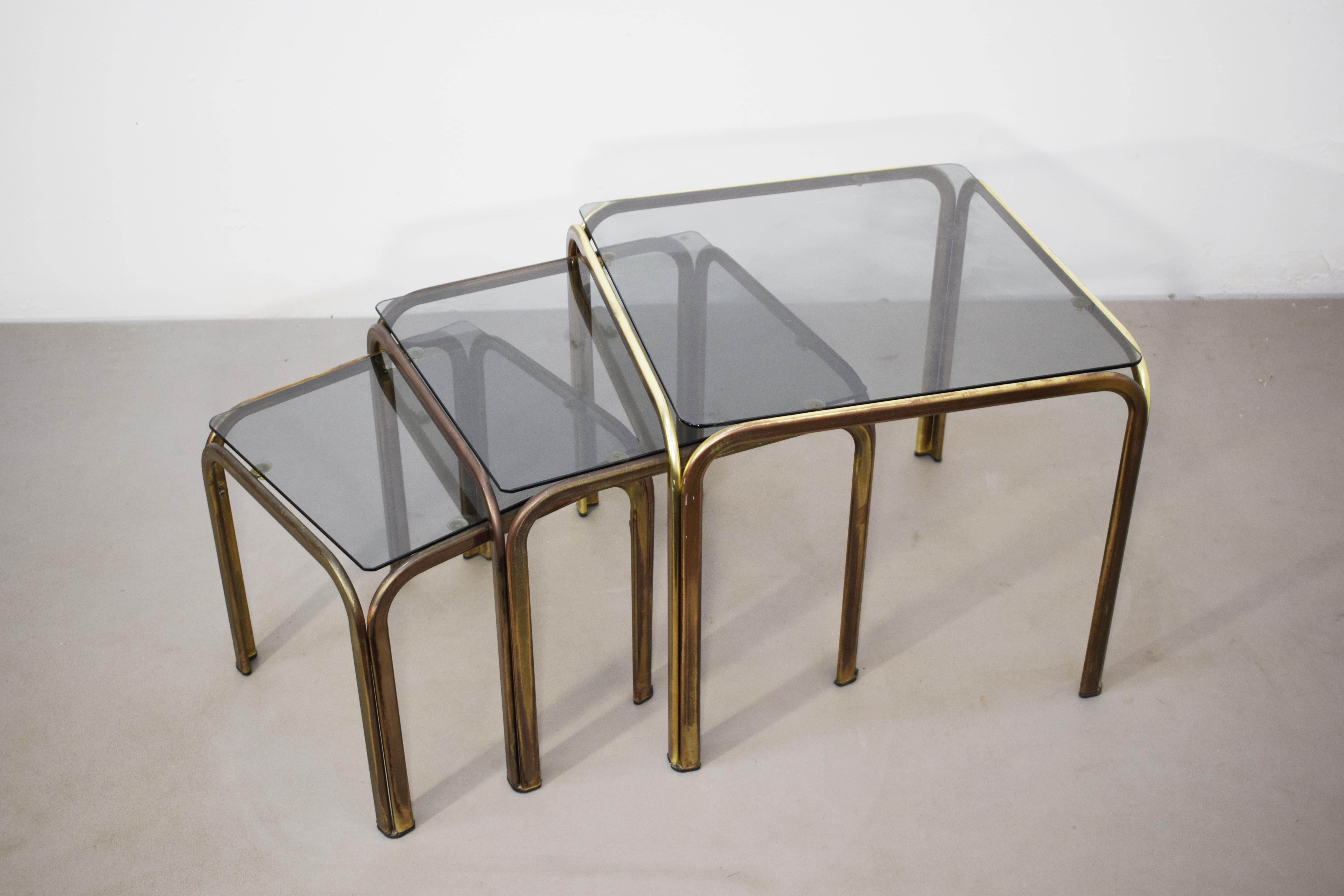 Satz von 3 stapelbaren Couchtischen, Messing und Rauchglas, 1970er Jahre.
1) 47x47 H=41 cm;
2) 39x39 H= 38 cm;
3) 33x33 H=  31 cm.