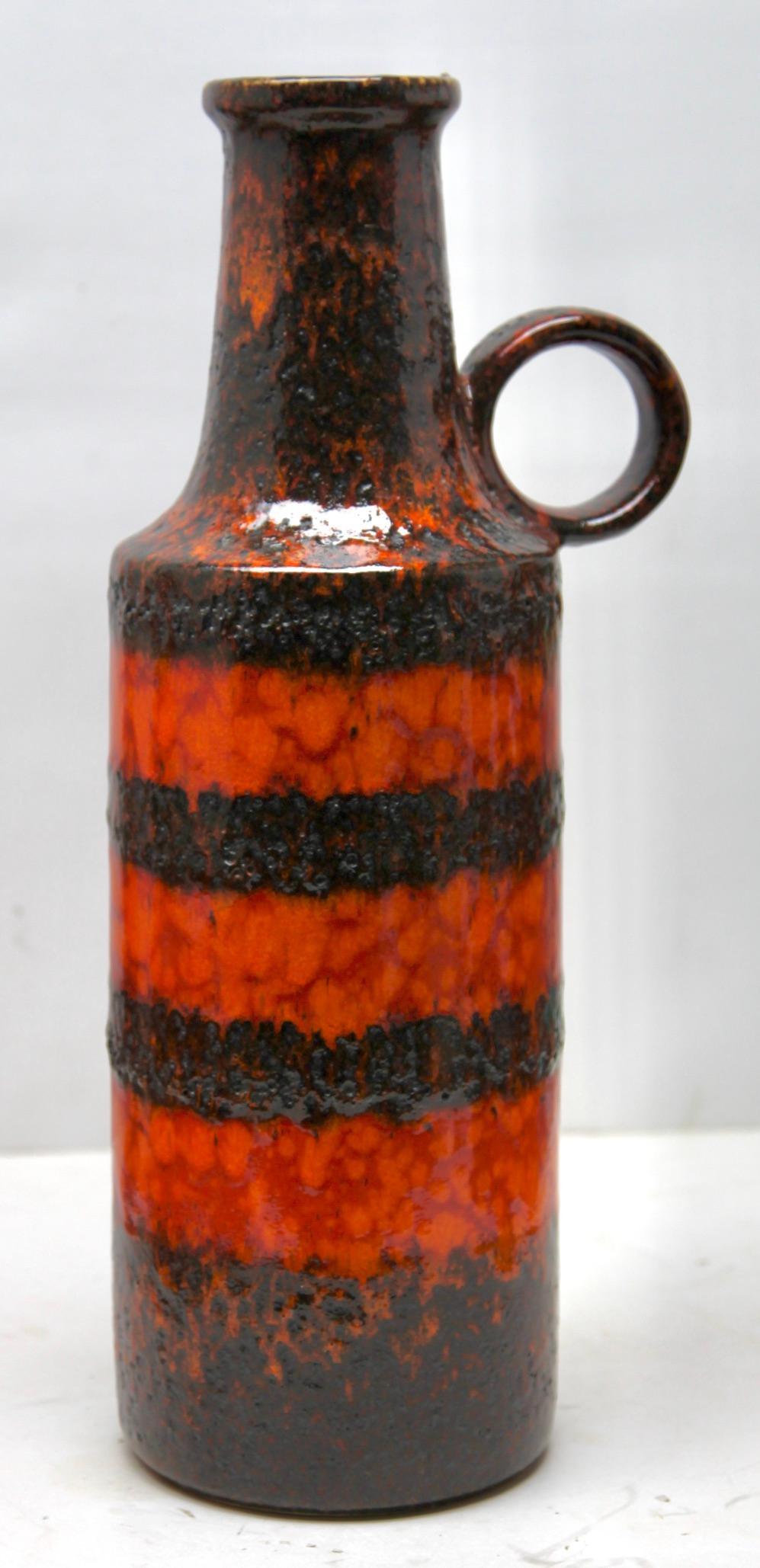 A classic 60s design. Of Fat lava handled vase in the classic sixties 'Sundown' decor; with a rough glaze of dark earth-colour over the yellow and red. 
From the Scheurich (Europ Linie) W-Germany. 
Hand decorated glaze.

Measure: 47 x 19 cm