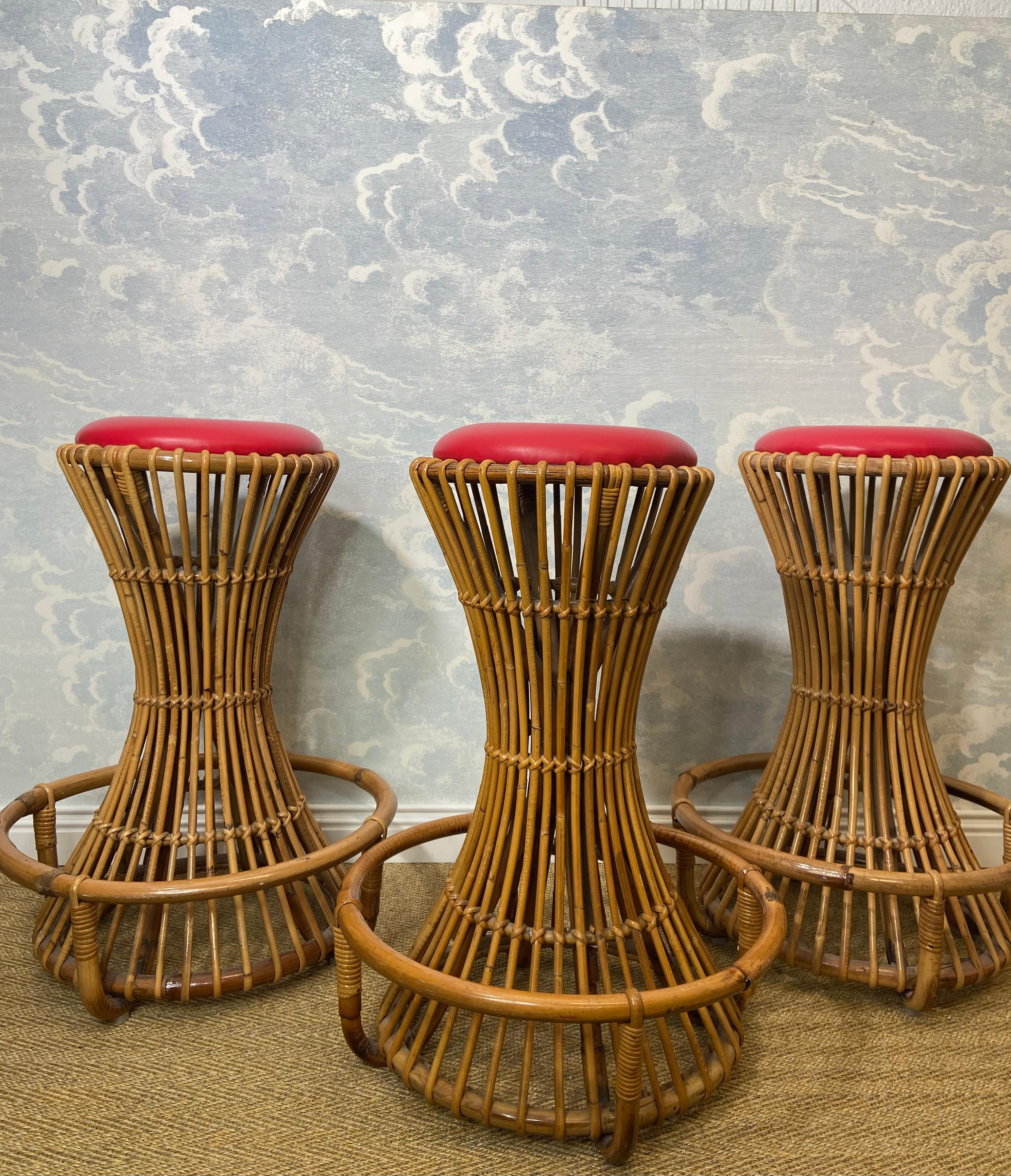 This sturdy set of 3 hourglass-shaped bar stools was design by Tito Agnoli and manufactured by Bonacina in Italy in the 1950s. 

Handcrafted from curved rattan and bamboo, these high quality bar stools are well proportioned and suitable for both
