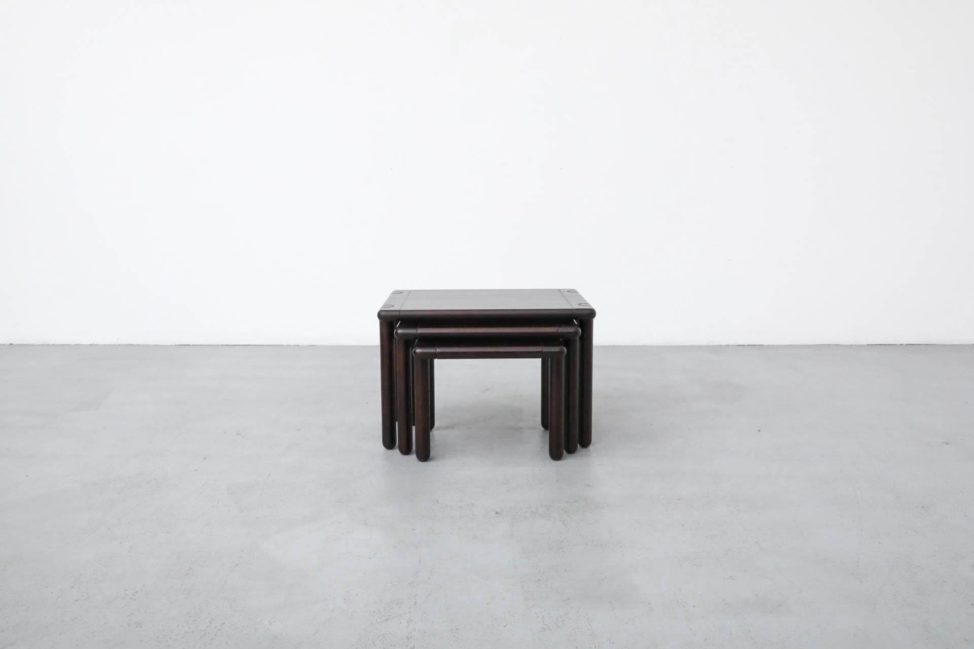 A beautiful set of three 1950s nesting tables, crafted in the sophisticated aesthetic of Tobia Scarpa style. Finished in a rich dark oak stain, these tables feature distinctive dark square frames with elegantly curved edges and slender round legs.
